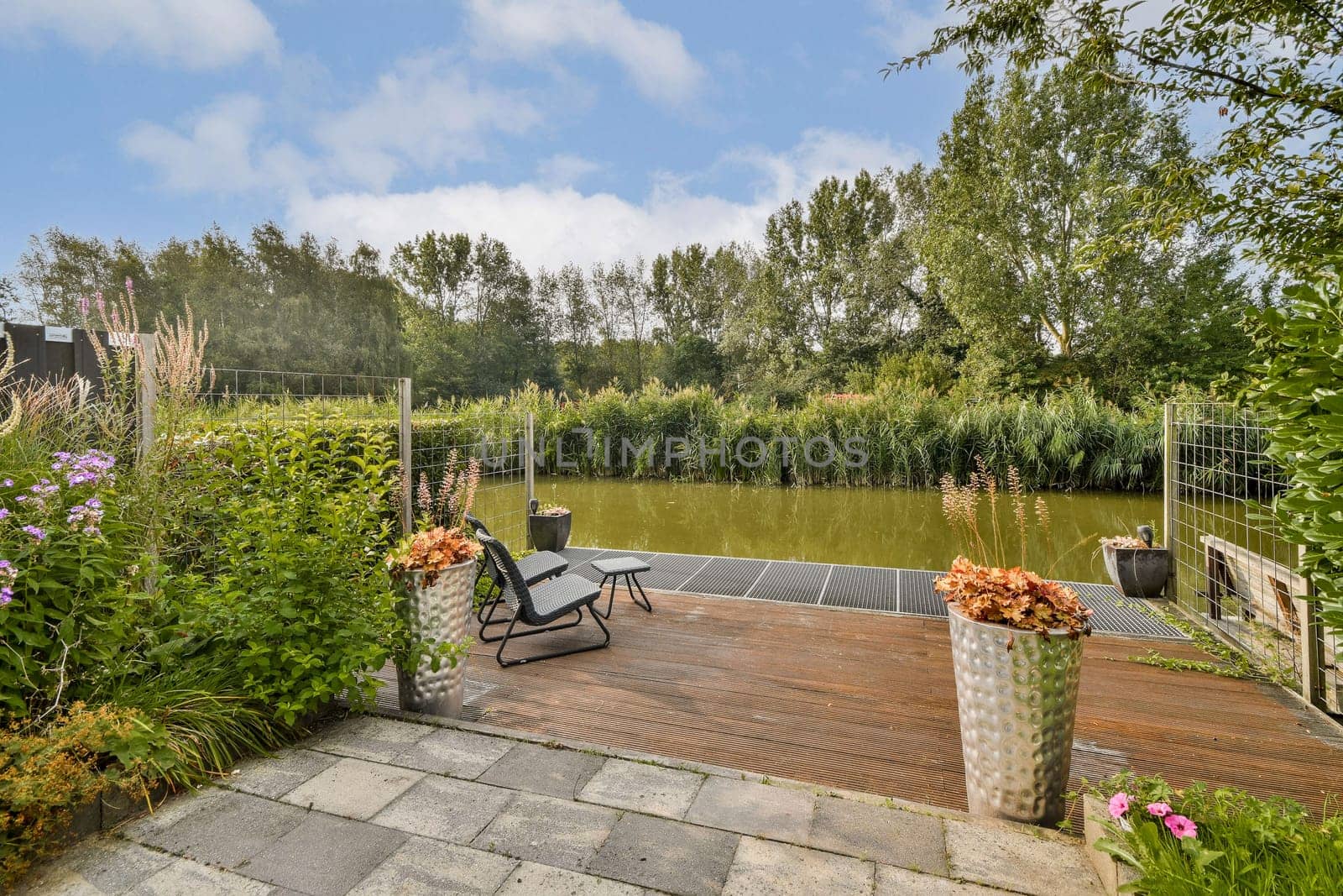 A peaceful garden scene featuring lush greenery, a calm water body, and decorative plants creating a relaxing atmosphere for outdoor enjoyment.