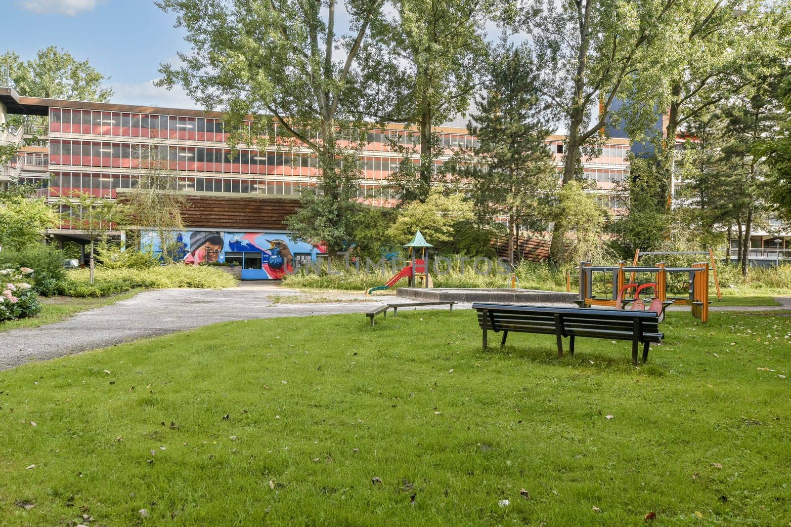 A serene park featuring lush greenery, pathways, and modern architecture in the background, perfect for relaxation and leisure activities.