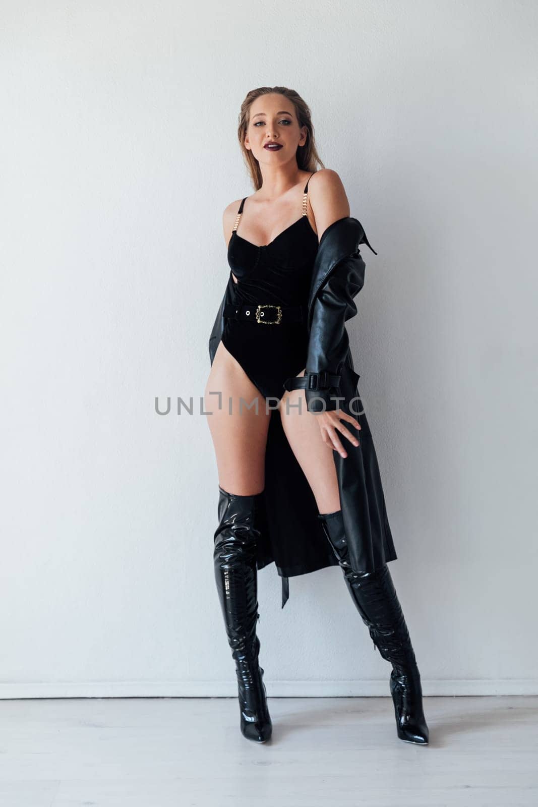 Fashionable slim woman in black leather raincoat and boots