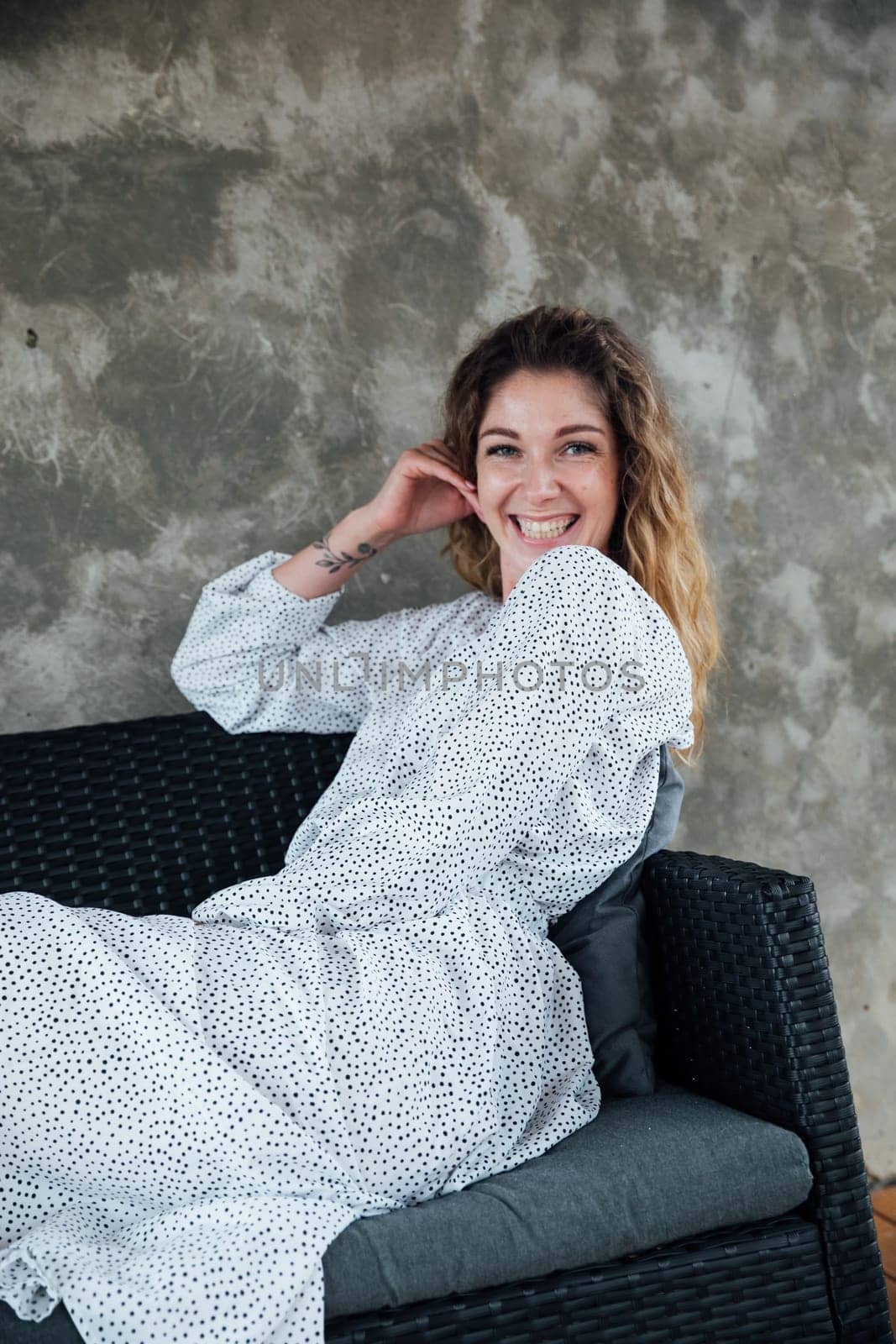 Fashionable woman in summer white dress smiling on gray background