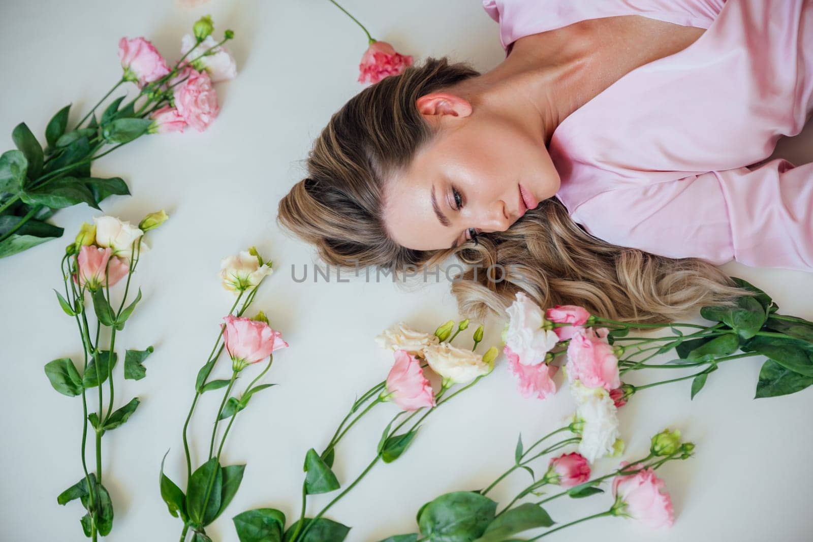 Fashionable woman in summer pink dress lying among flowers