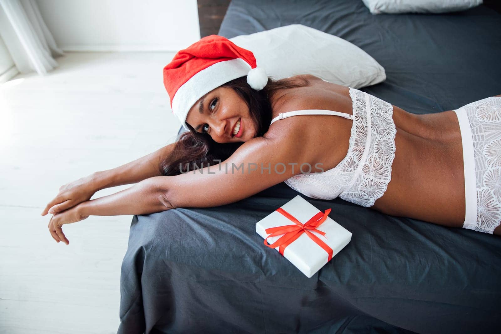 Woman in lingerie with christmas gift in bedroom on bed