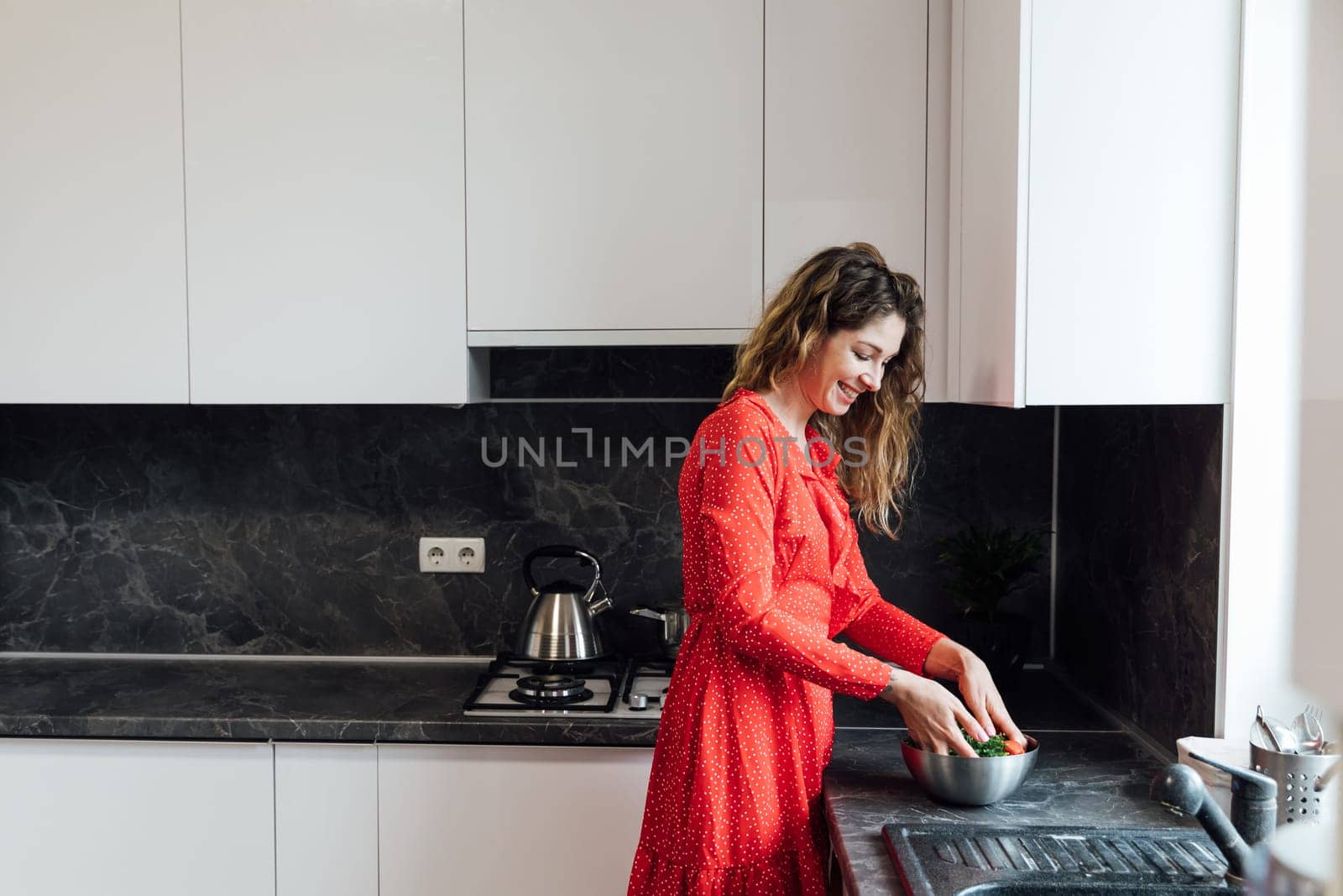 Woman in red dress preparing food in kitchen for dinner