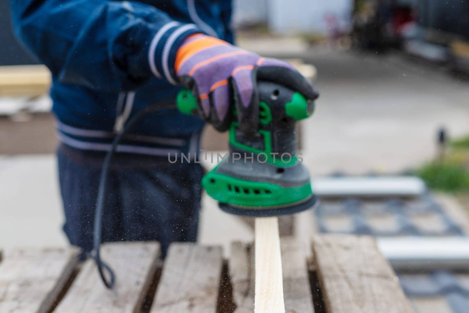 Man sanding wooden boards. Selective focus. People.