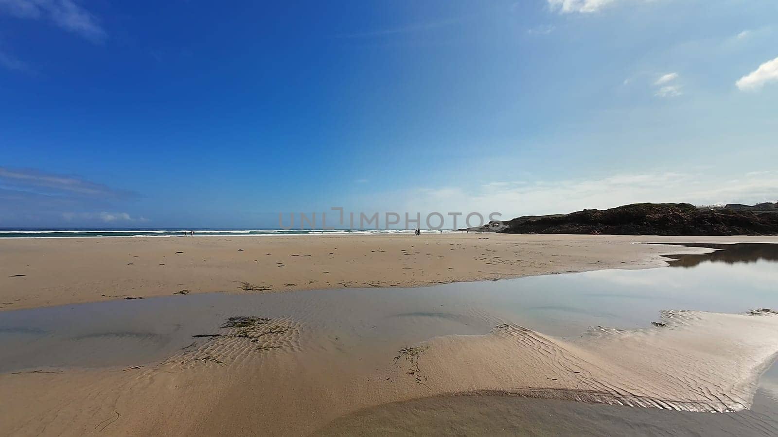 A beautifully tranquil beach scene featuring soft white sand, stunning reflections, and a vibrant blue sky above