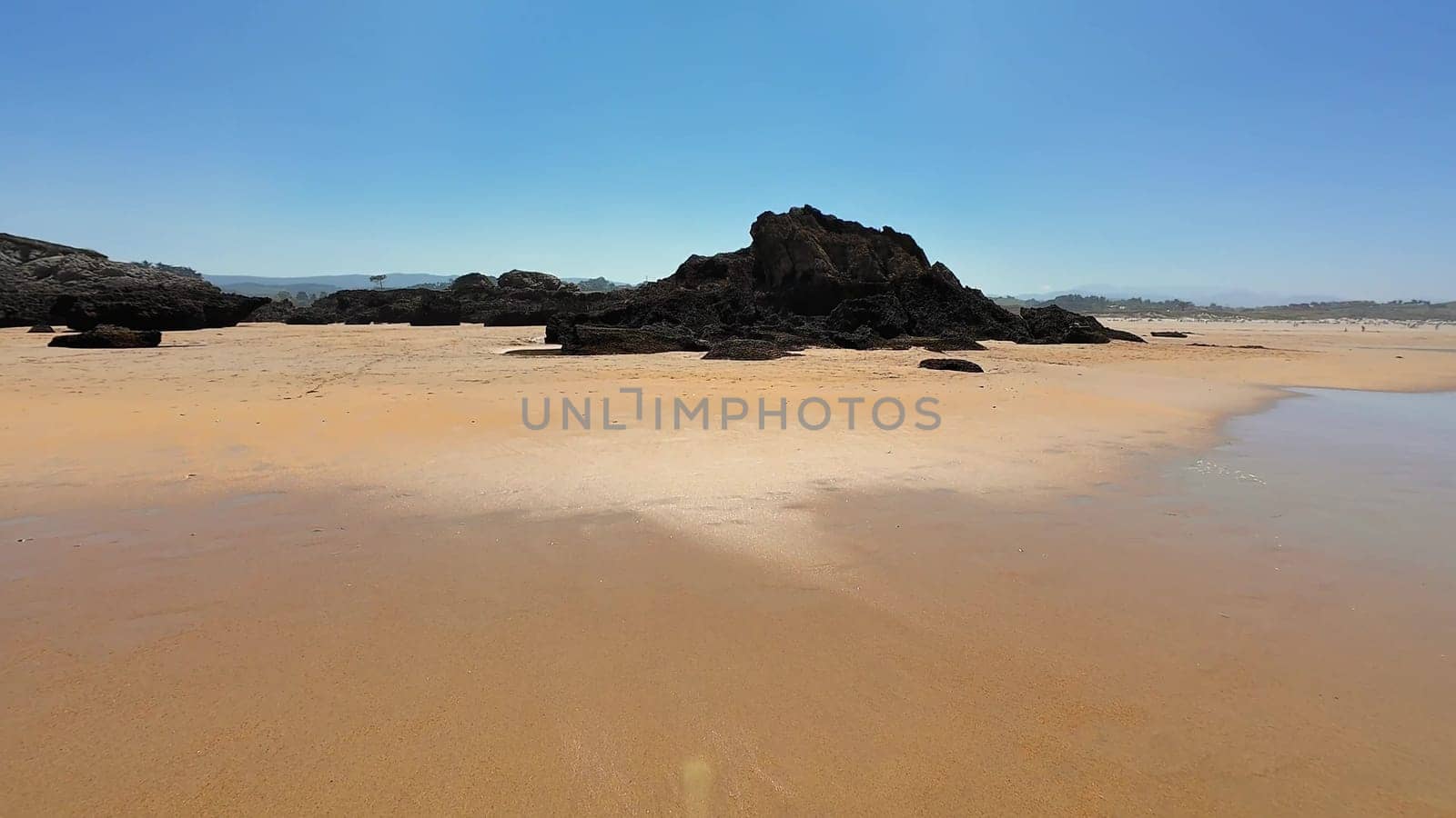 A serene beach with golden sands, rocky outcrops, and a breathtaking blue sky, inviting exploration