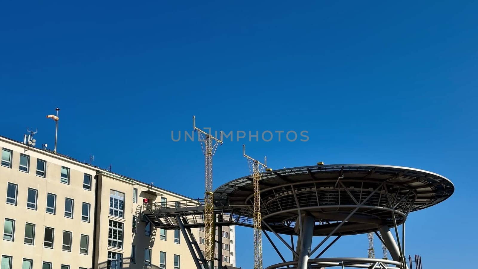 A contemporary communication tower setup is placed adjacent to a building beneath a bright and clear blue sky