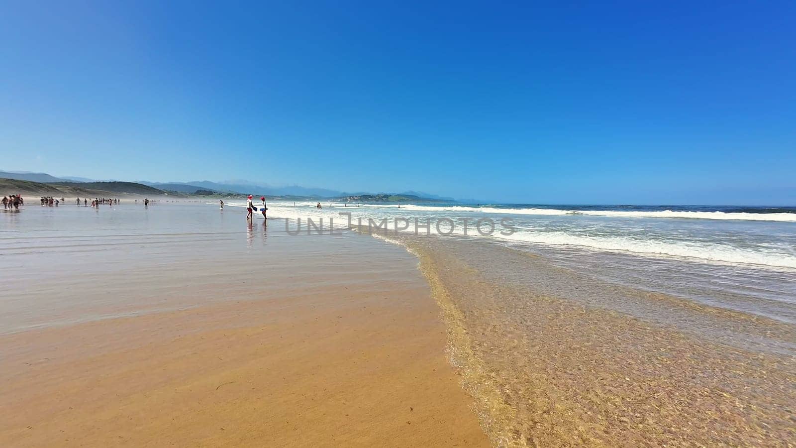 A tranquil beach scene showcasing clear blue skies and soft ocean waves gently lapping on the sandy shore