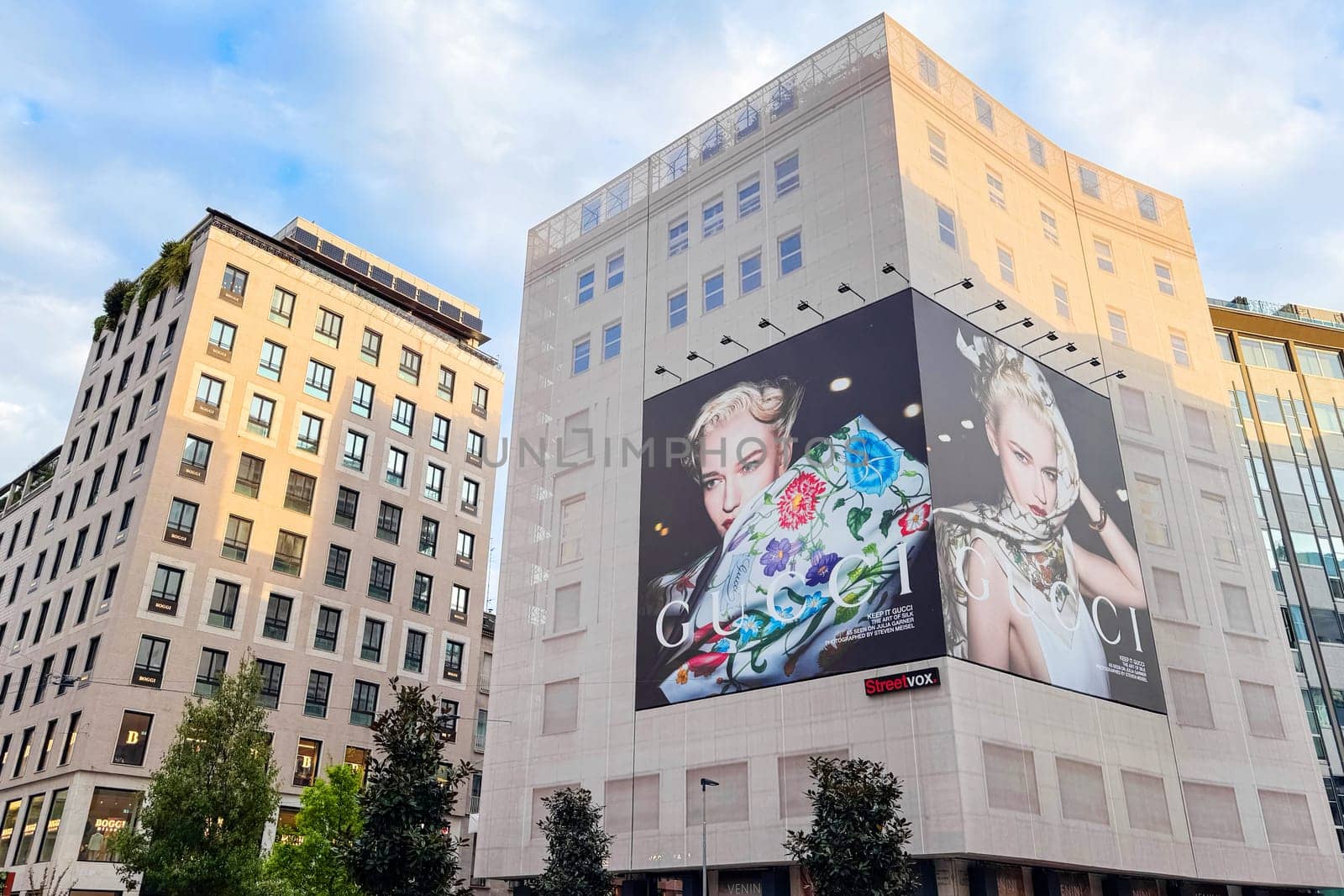 Milan, Italy - April, 12, 2025: Massive Gucci billboard with floral scarf campaign displayed on building in central Milan. High fashion ad, luxury branding.