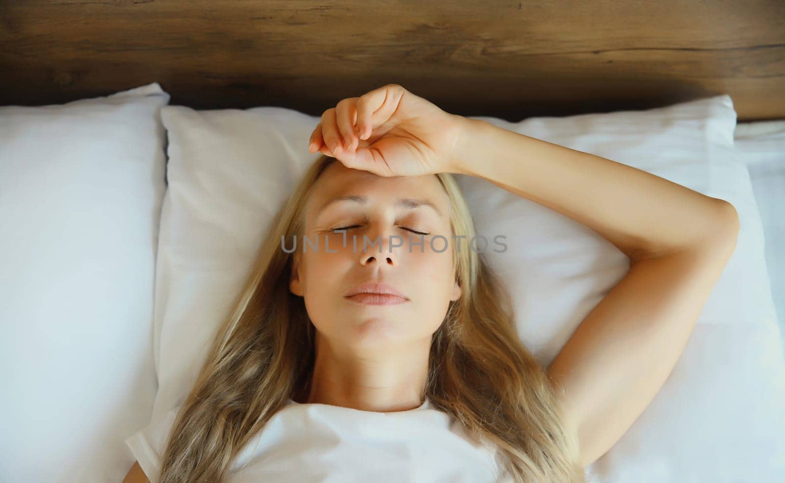 Exhausted tired woman touching head, suffering from headache, stress, fatigue, temples pain, migraine, loud noise, tension lying on the pillow in bed in bedroom at home