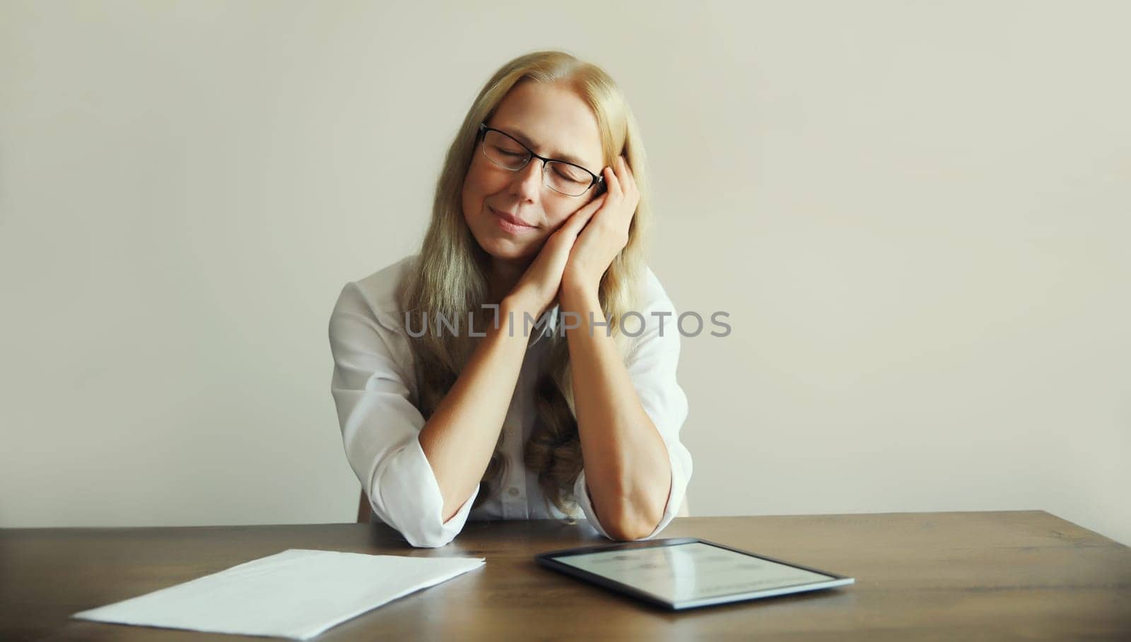 Tired overworked sleeping woman employee while working with digital tablet computer and paper documents sitting at desk in office in morning
