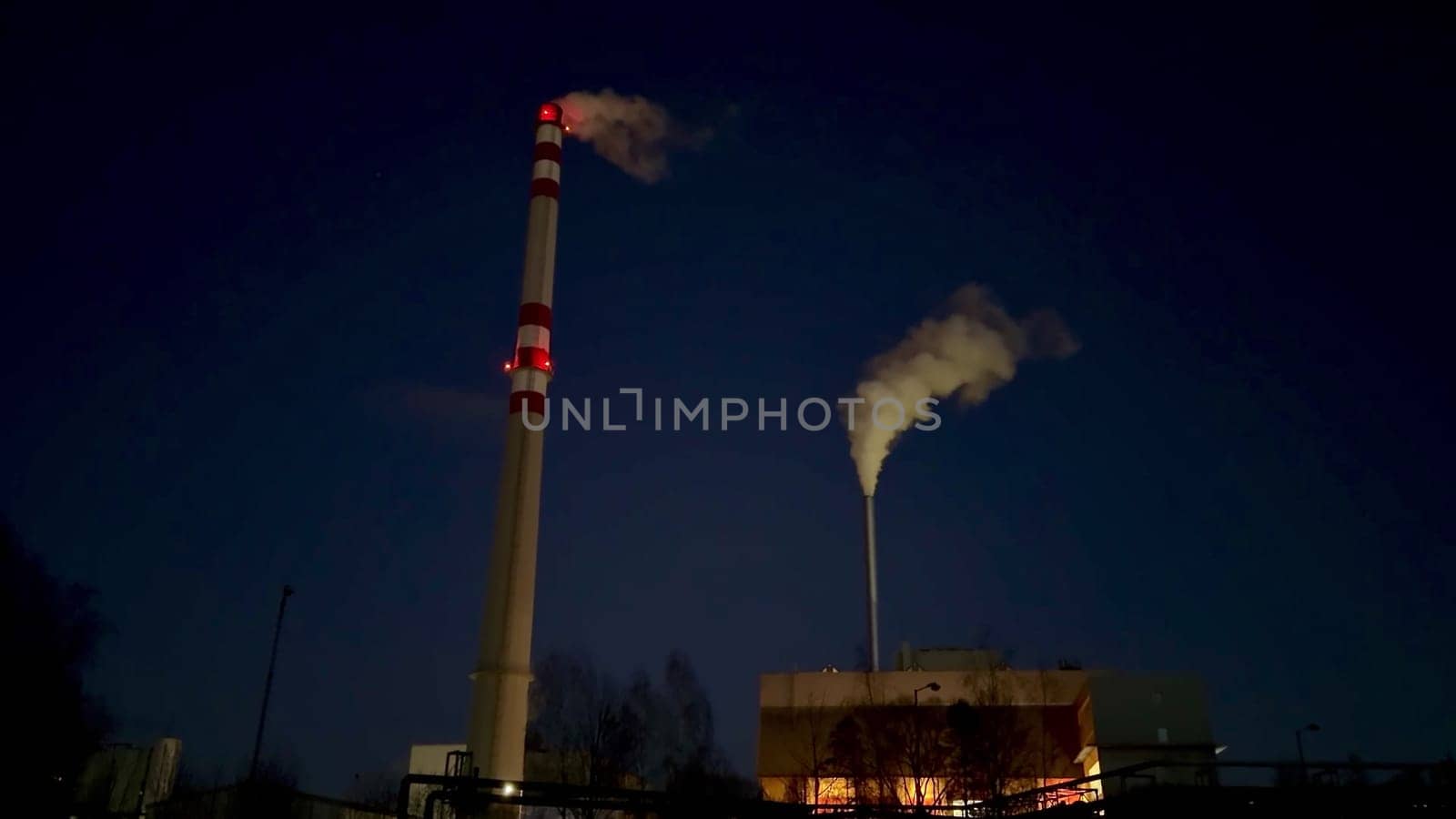 The captivating night view showcases smokestacks emitting both steam and smoke from an industrial facility