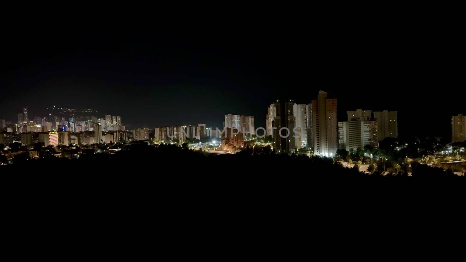 A stunning panoramic view of a city skyline at night, showcasing illuminated buildings and vibrant lights.
