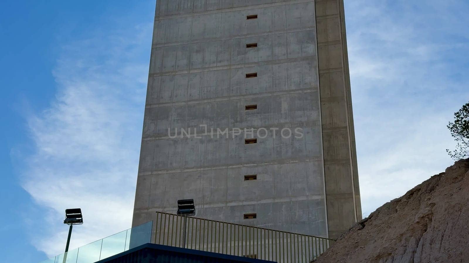 A tall, striking concrete tower is silhouetted against a stunningly clear blue sky, showcasing modern architecture