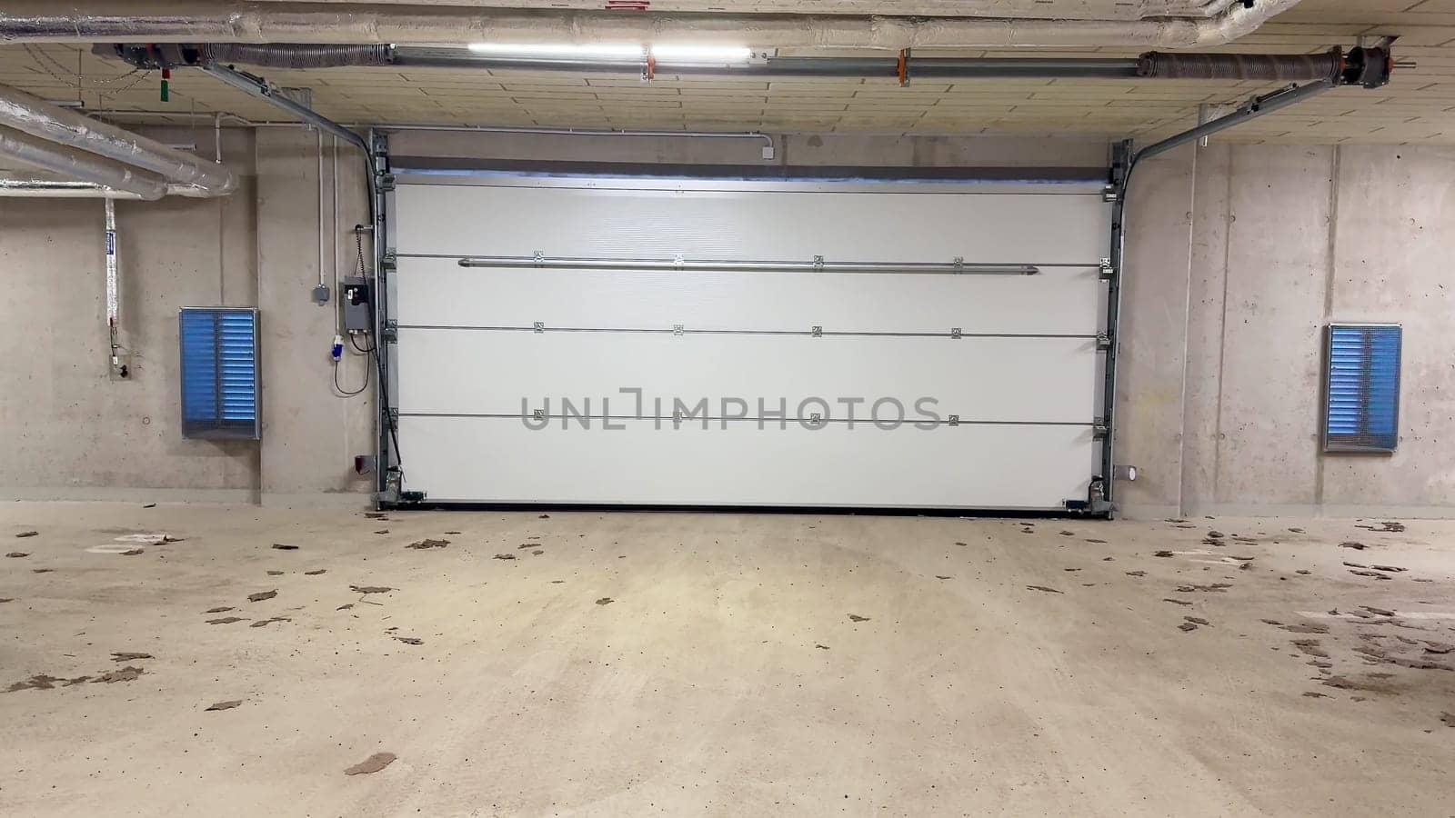 A wellorganized and clean garage space that features a stylish modern white garage door along with concrete walls