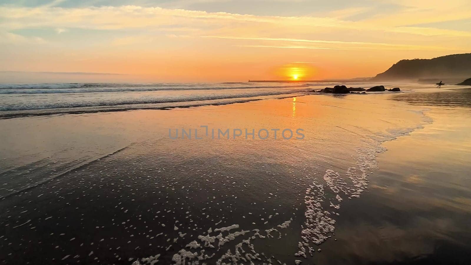 This is a captivating view of a beautiful sunset reflecting on the calm ocean waves by the serene beach