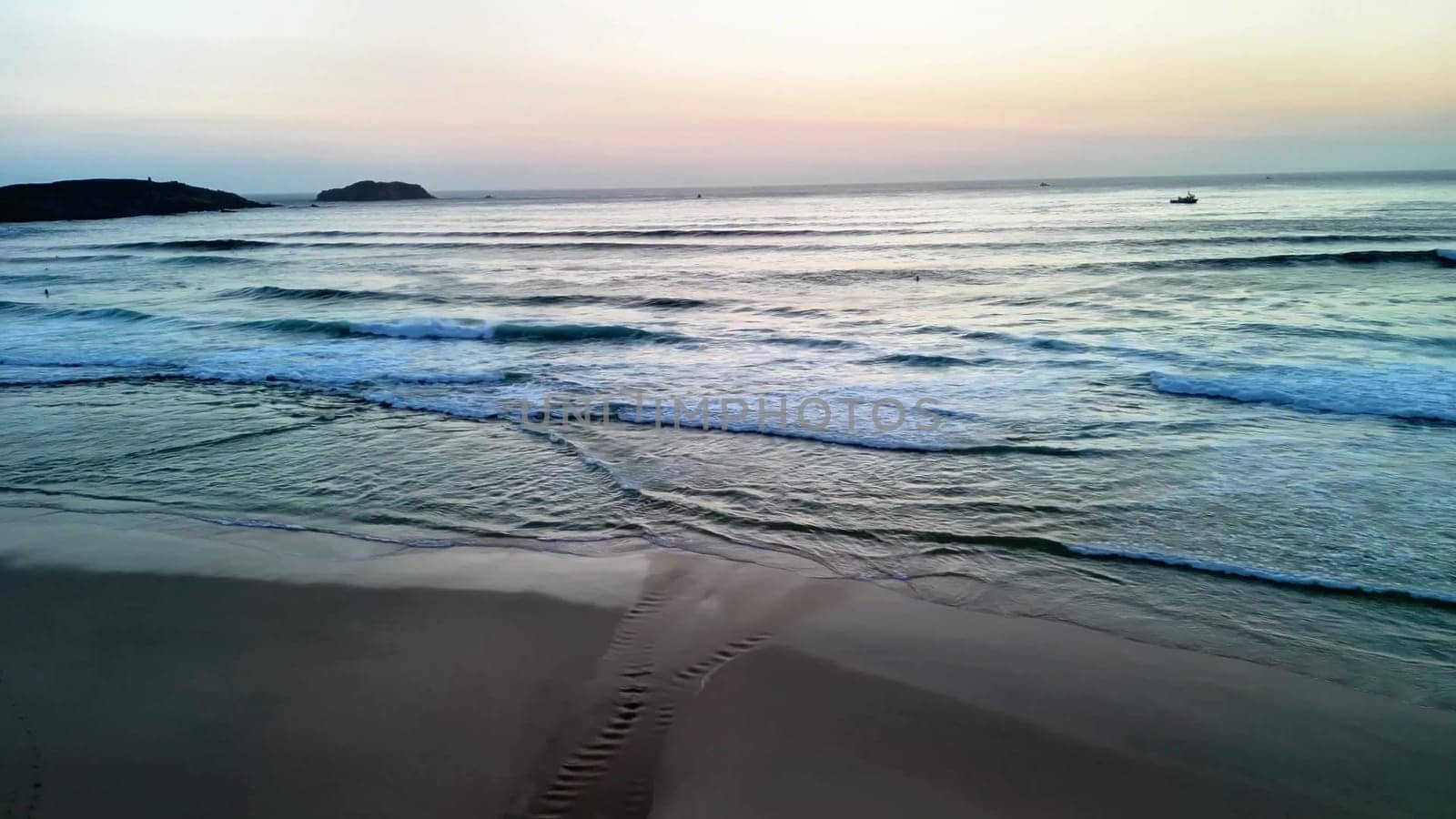 A serene and tranquil beach scene at sunset featuring gentle waves lapping softly against the shore