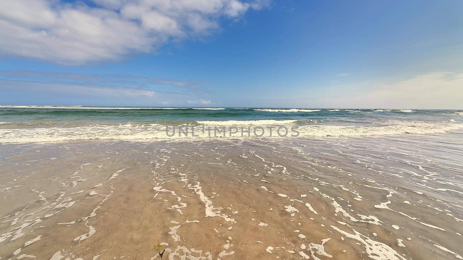 Delight in the soothing tranquility brought by ocean waves gently lapping against the warm, inviting shore