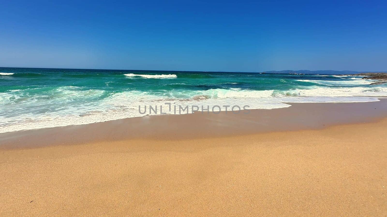 Experience a tropical beach paradise with vibrant azure waves, soft golden sand, and a clear blue sky