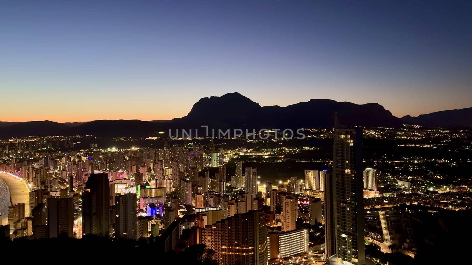 A breathtaking urban city skyline, beautifully illuminated at night, set against a vibrant dusk sky full of colors