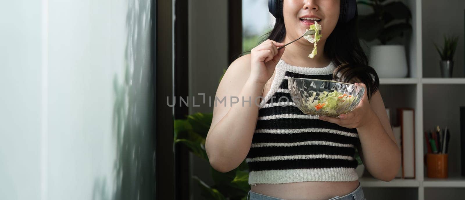 A young woman enjoys a healthy meal, showcasing a balanced lifestyle with fresh vegetables in a cozy home setting.