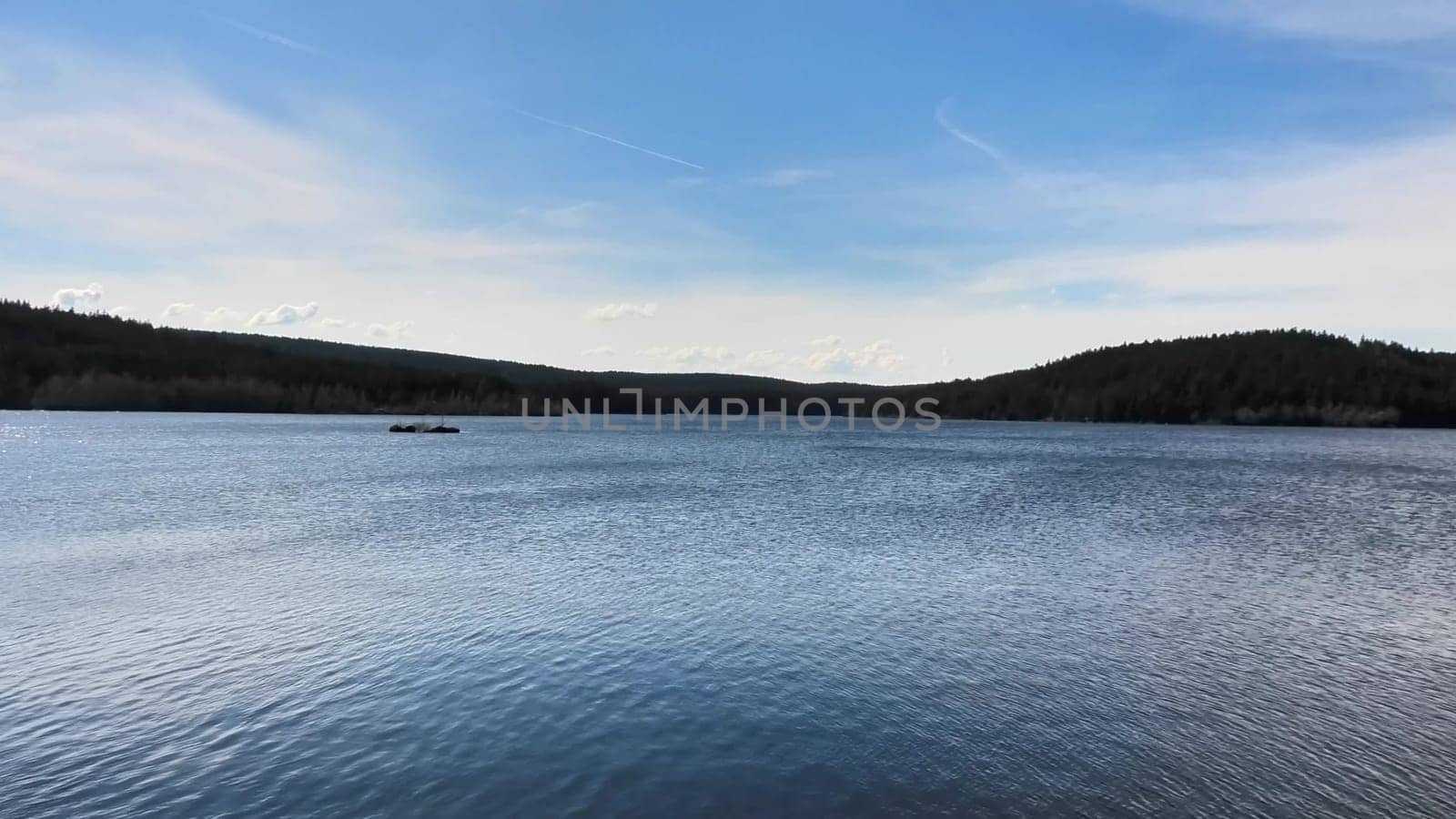 A tranquil and serene lake landscape beautifully surrounded by lush green forests beneath an expansive clear blue sky