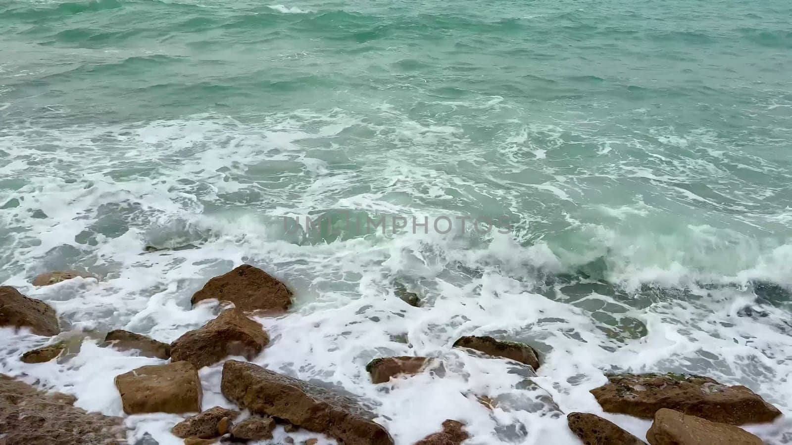 Witness the serene beauty of powerful waves crashing against rugged rocks, showcasing natures artistic power