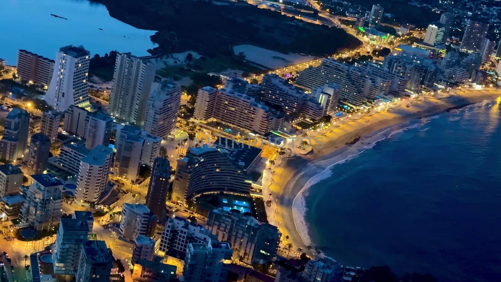 A breathtaking aerial view brilliantly showcasing the illuminated cityscape and stunning coastline at night