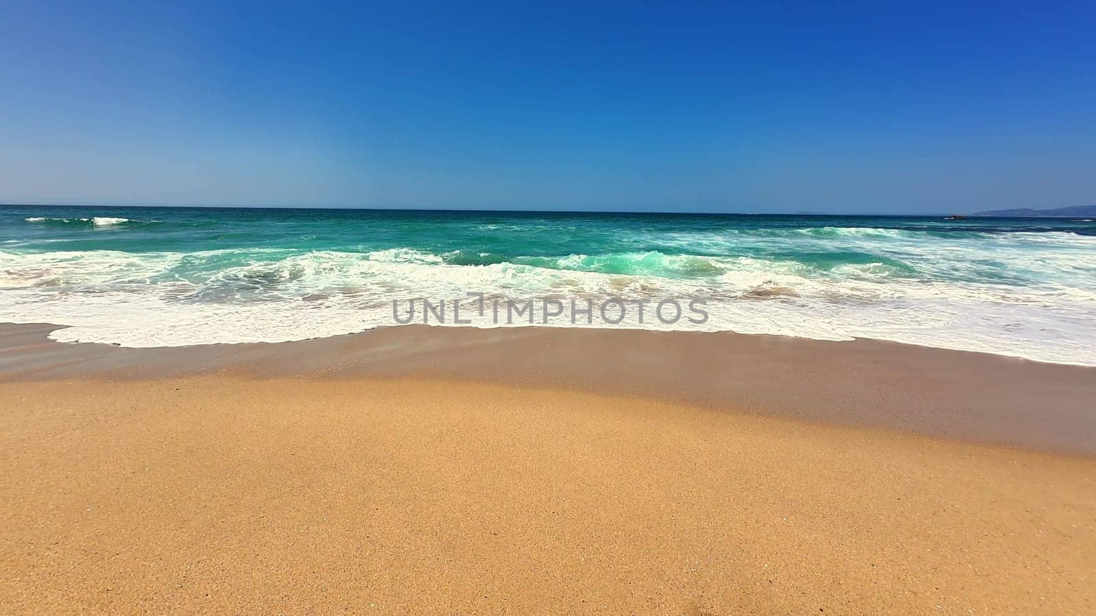 A serene and tranquil beach scene featuring gentle waves lapping against soft golden sand under a clear blue sky