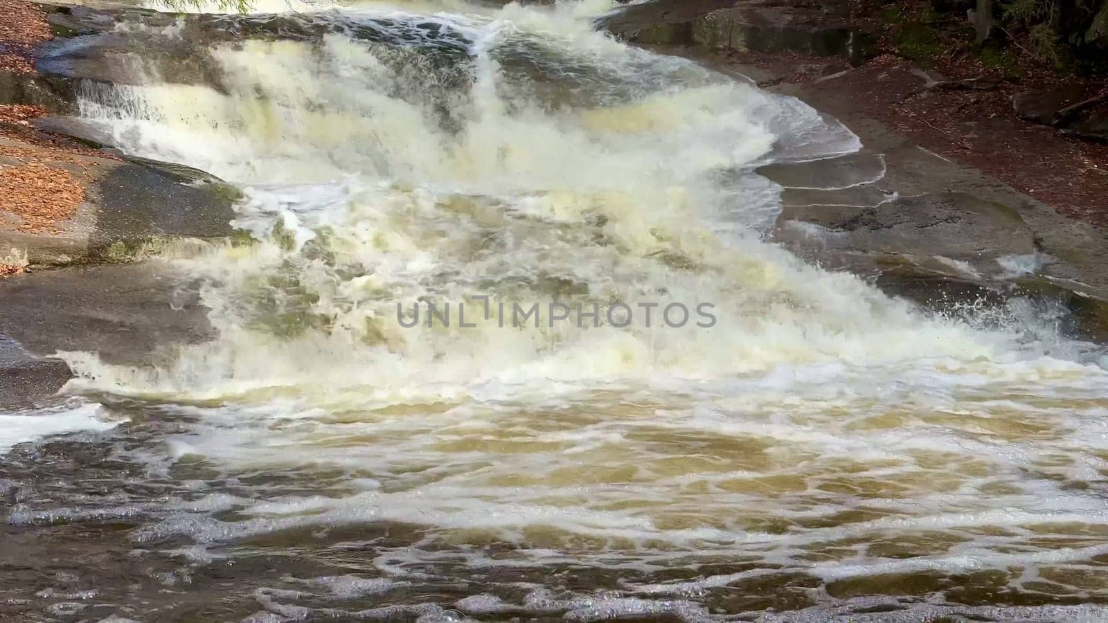 A stunning view of a magnificent waterfall cascading over rugged rocks, with foamy water flowing below