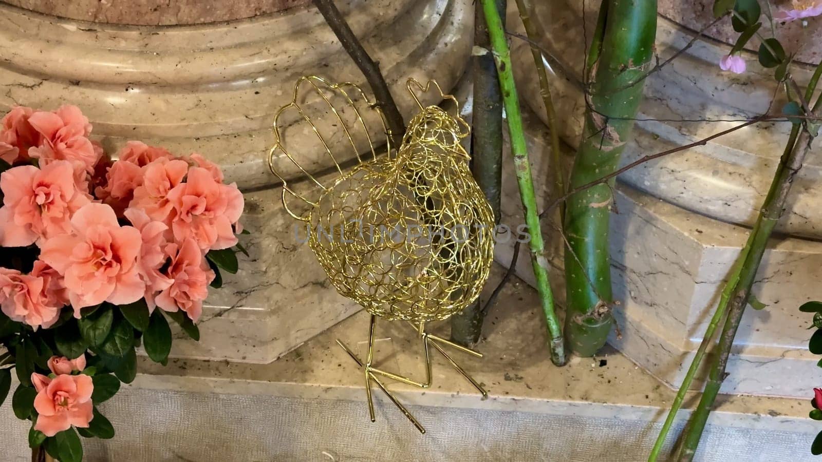 A crafted wire chicken ornament among vibrant flowers, showcasing creativity and charm in its design