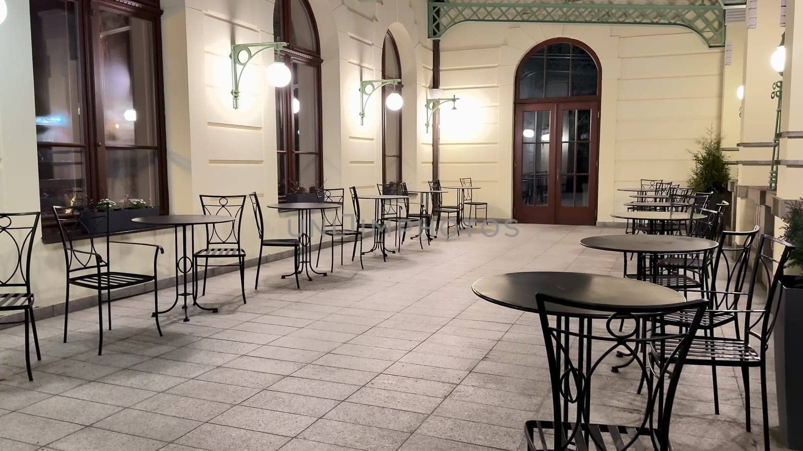 The cozy night view features empty outdoor cafe tables softly illuminated, enhancing the inviting atmosphere