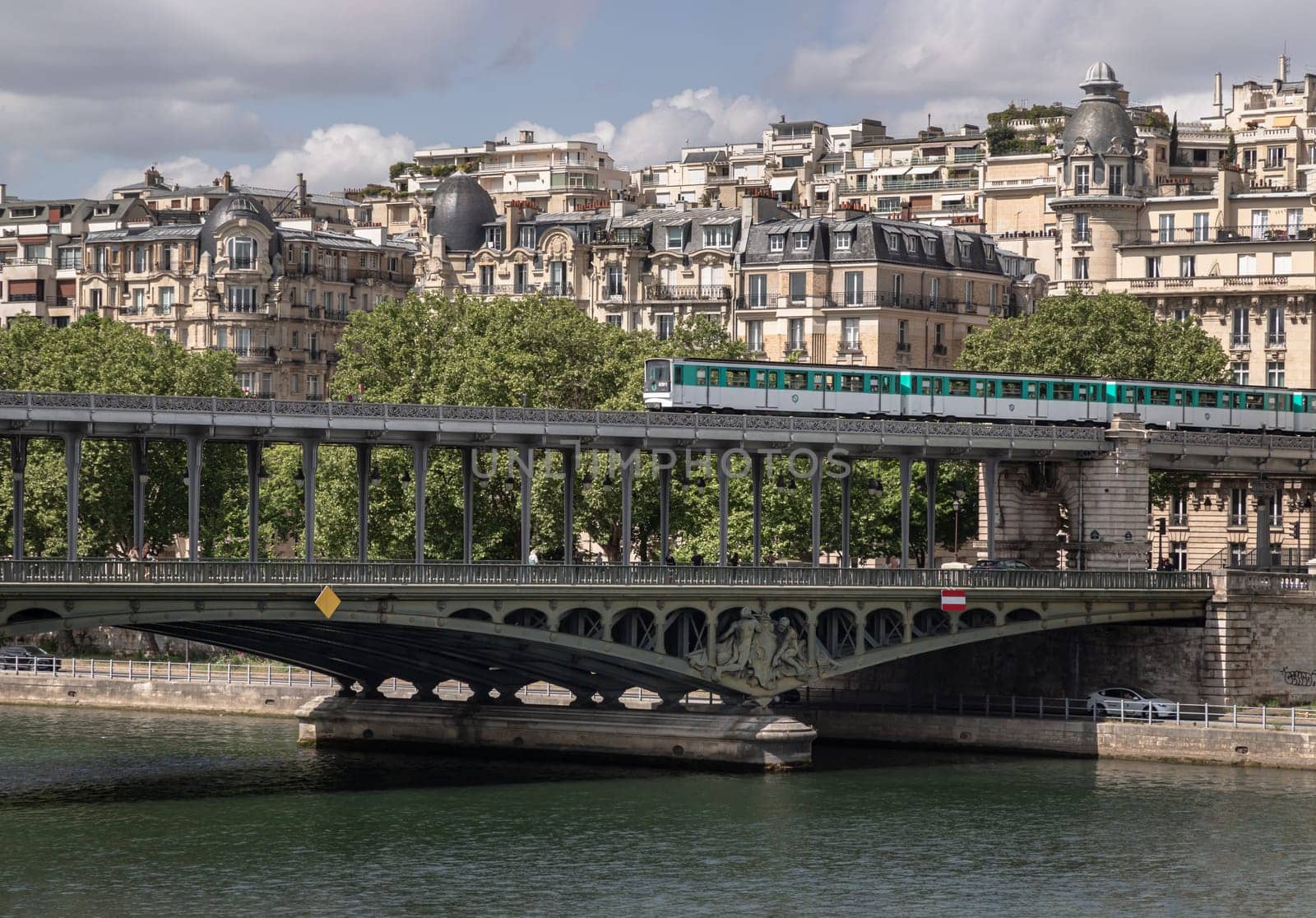 France, Paris - May 03, 2025 - Stunning view of A metro train crossing the Pont de Bir Hakeim bridge with typical parisian buildings in the background over the Seine river in Paris. Sculptures decorating the two-level bridge built (Steel bridge), Destinations in Europe. use it as your Wallpaper, Poster and Copy space, Selective focus.