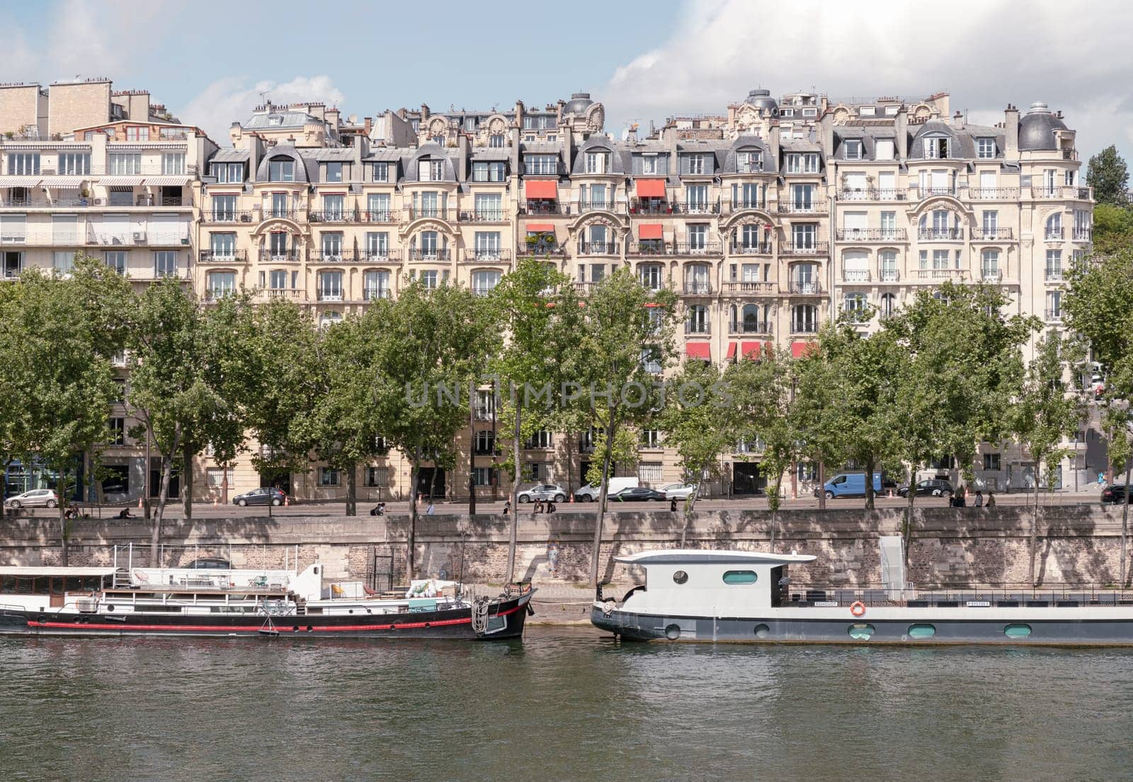 France, Paris - May 03, 2025 - Scenery view of River cruise docking along River seine banks with Haussmannian architectural residential buildings in the background. use it as your Wallpaper, Poster and Space for text, Selective focus.