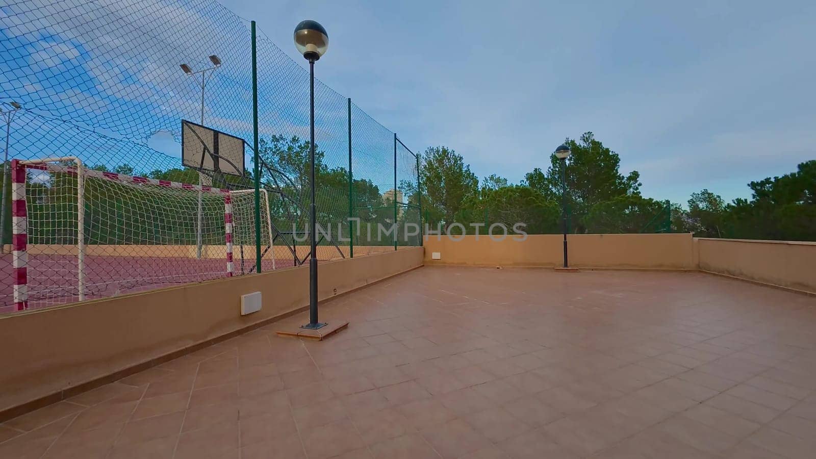 A vibrant sports area that features a basketball court beautifully surrounded by lush greenery and trees