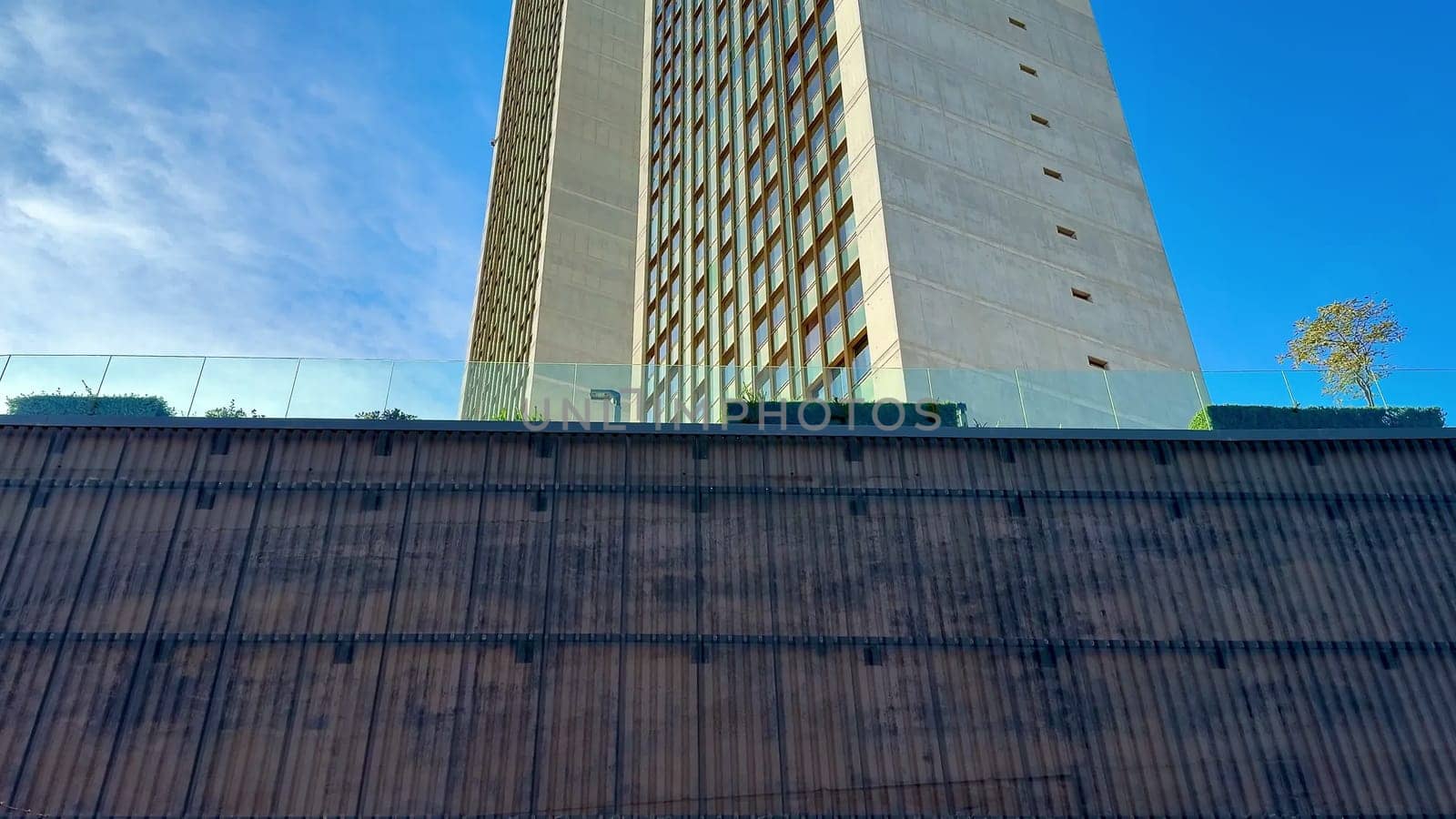 A breathtaking view of a modern contemporary skyscraper extending high into the clear, vibrant blue sky