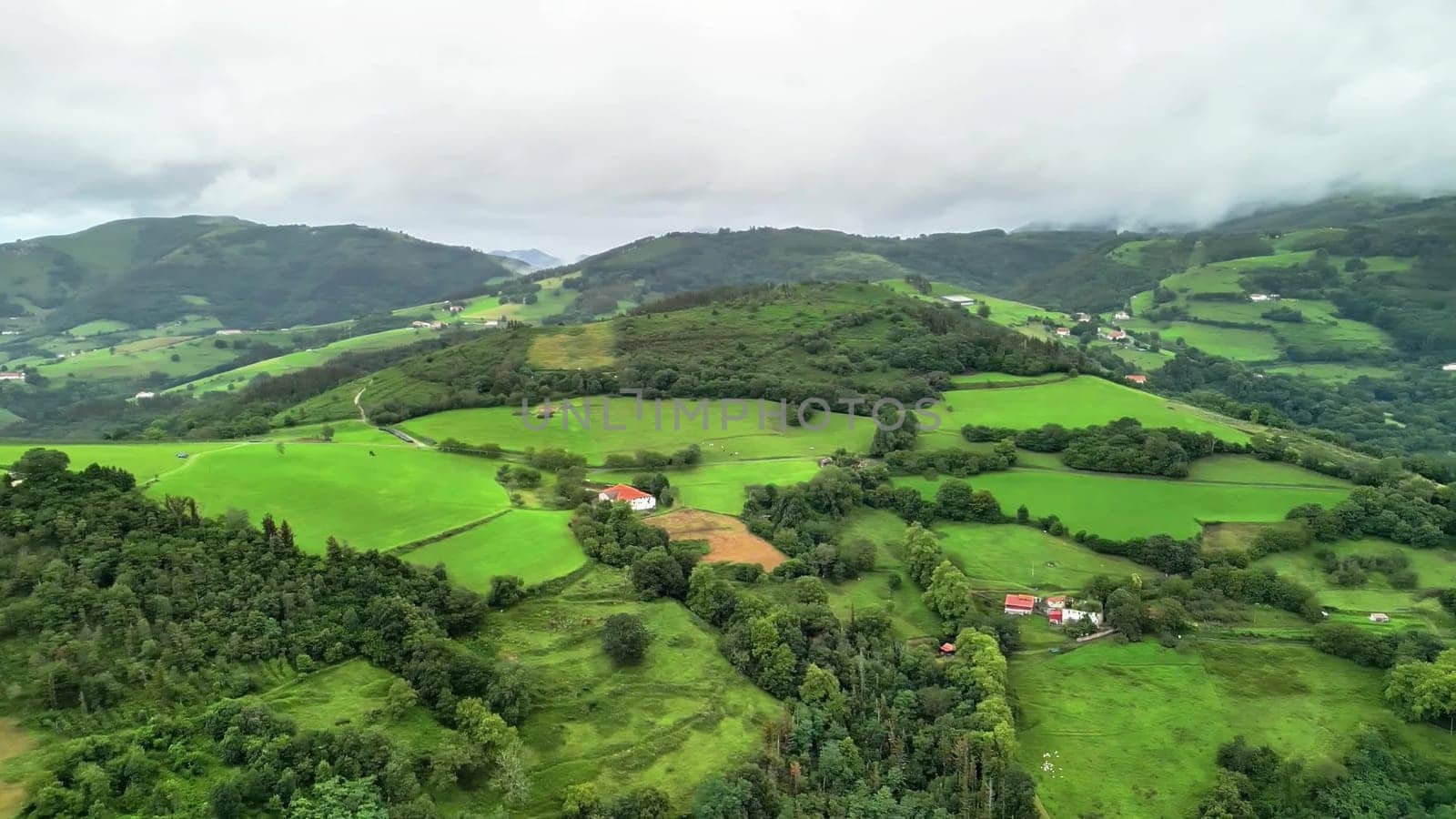 Stunning aerial footage beautifully showcases vibrant green fields and rolling hills set against a cloudy sky