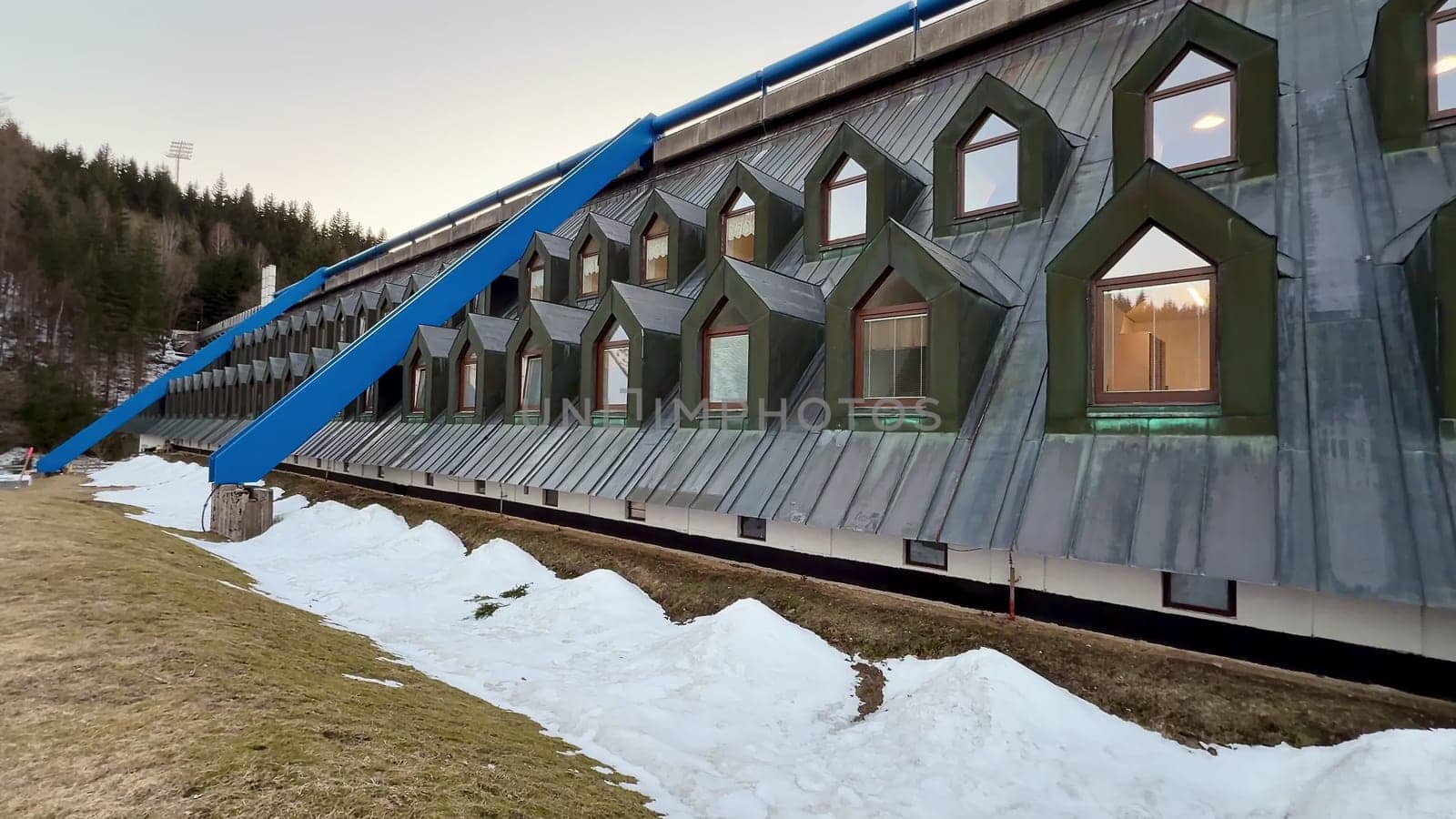 This innovative building showcases striking geometric windows set against a picturesque snowy backdrop