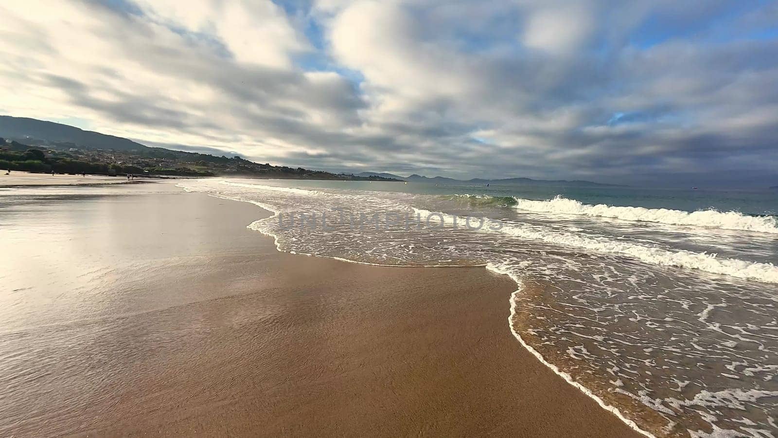 A beautiful and serene beach landscape that showcases gentle, rolling waves and an incredibly picturesque cloudy sky