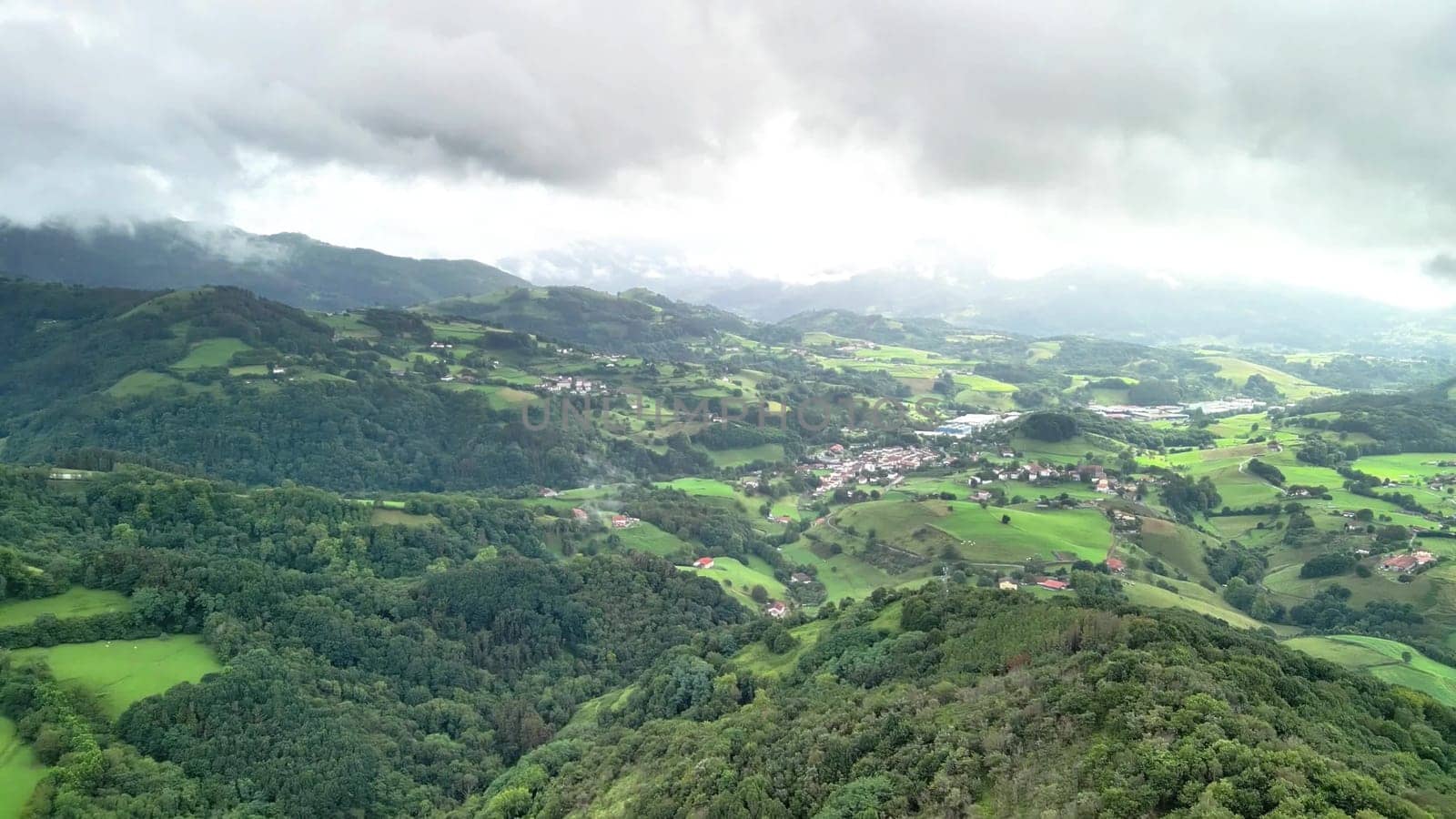 A stunning aerial view highlights vast green valleys, rolling hills, and picturesque villages in a serene landscape