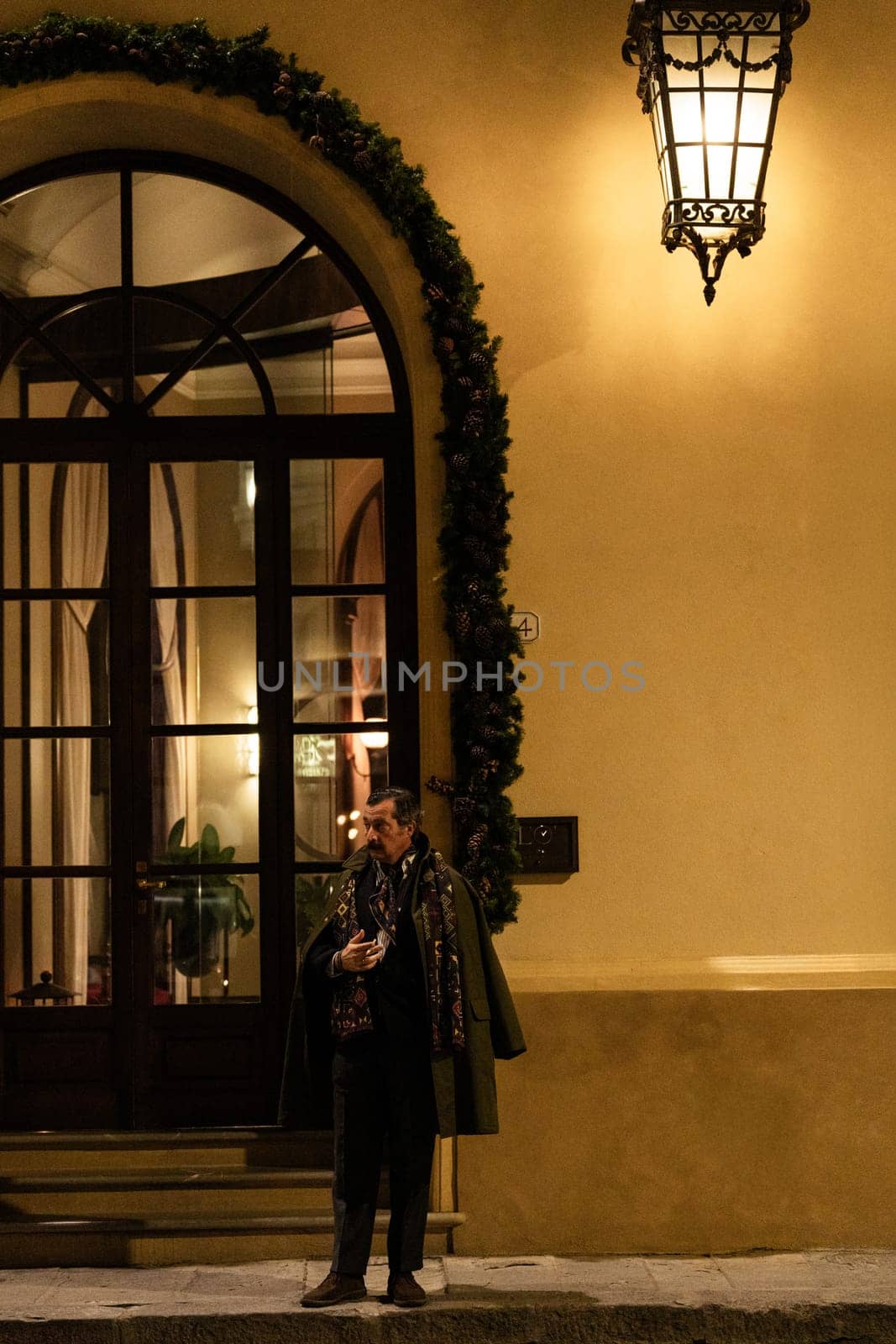 Florence, Italy - 12.01.2023: Elegant evening outing in front of decorated building under streetlamp glow.
