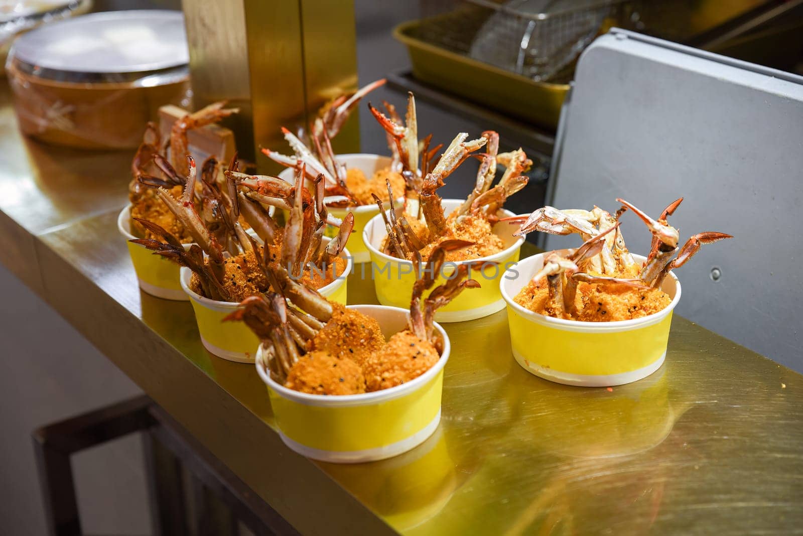 Crispy fried crab claws served in yellow paper bowls at a Shanghai street food stall. Crunchy texture and golden coating ready to eat