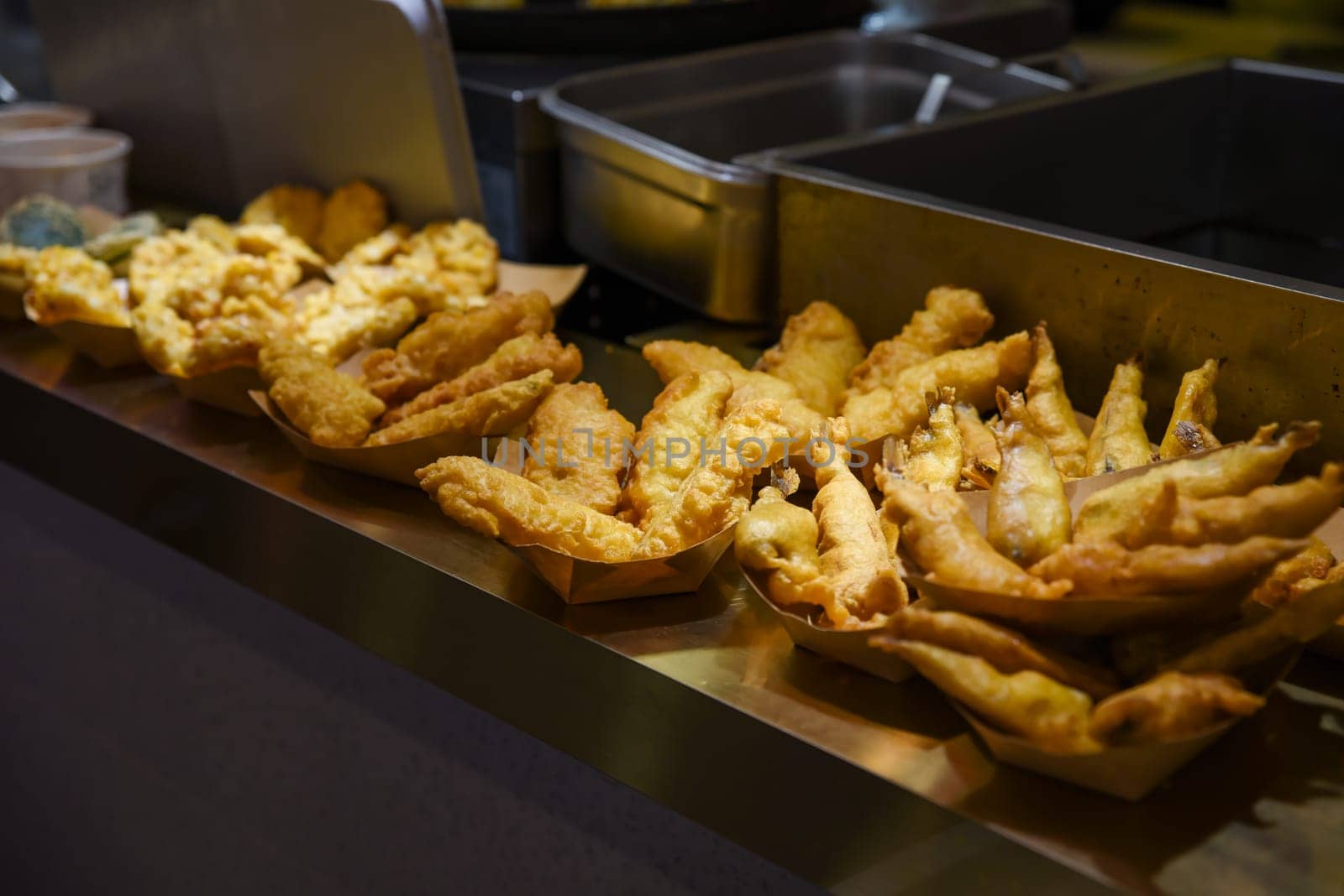 Golden battered fish fillets displayed in paper trays at a Chinese street food stall. Hot, crunchy and freshly deep-fried in oil