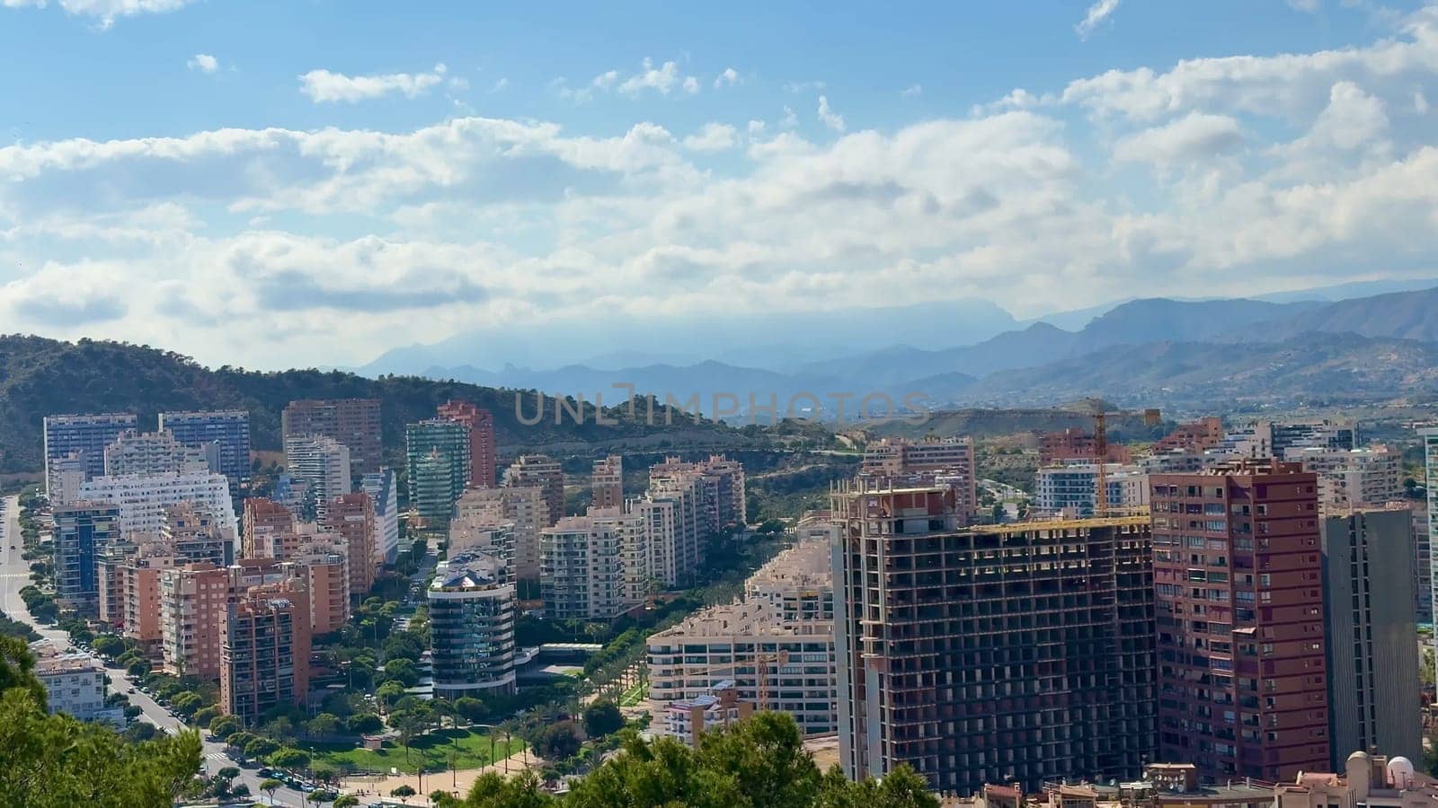 A breathtaking view showcasing a modern cityscape intricately surrounded by picturesque mountains and wispy clouds