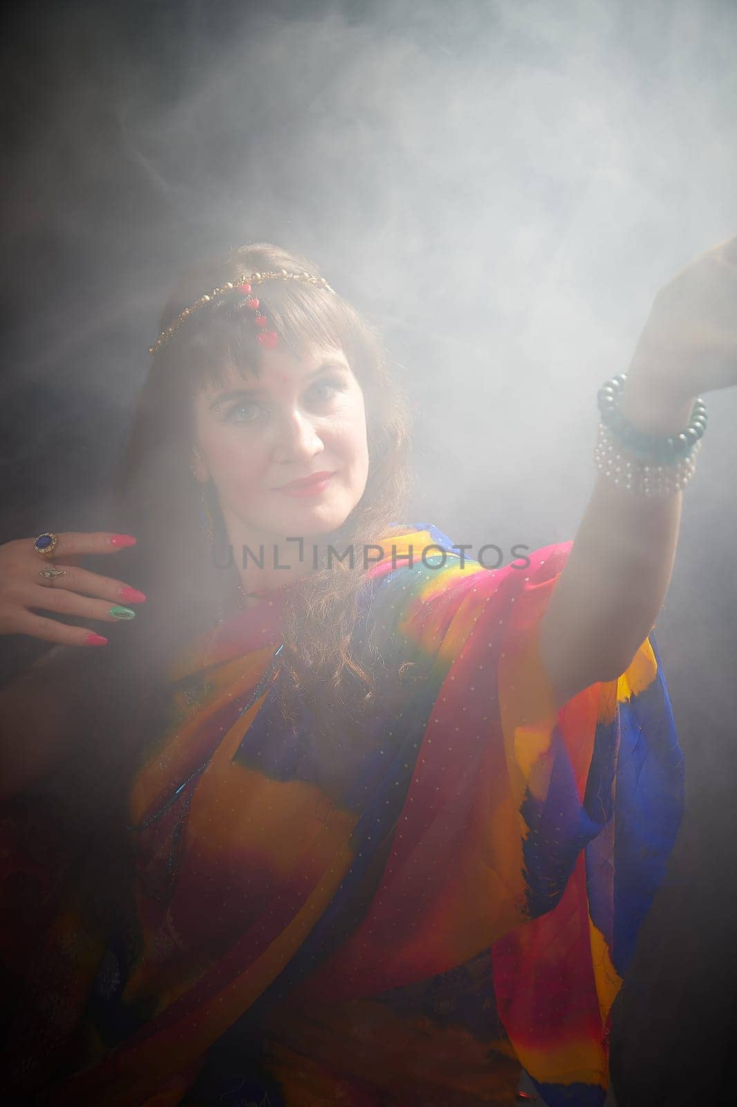 A woman with blonde hair showcases her beauty in a colorful sari, surrounded by a mystical fog in a creative Indian photoshoot.