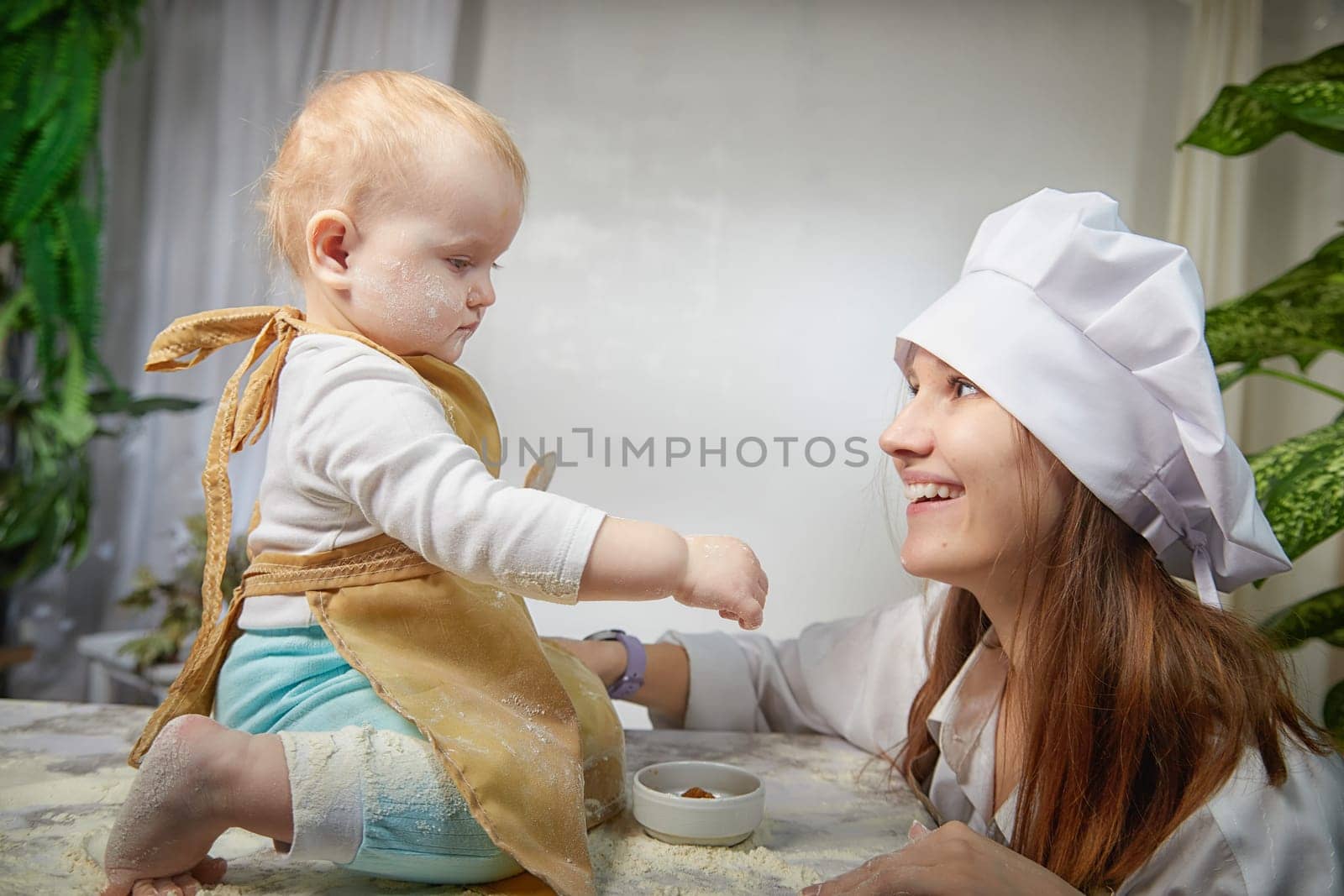 A mother and daughter joyfully engage in a flour-filled moment, creating memories in a cozy kitchen setting.