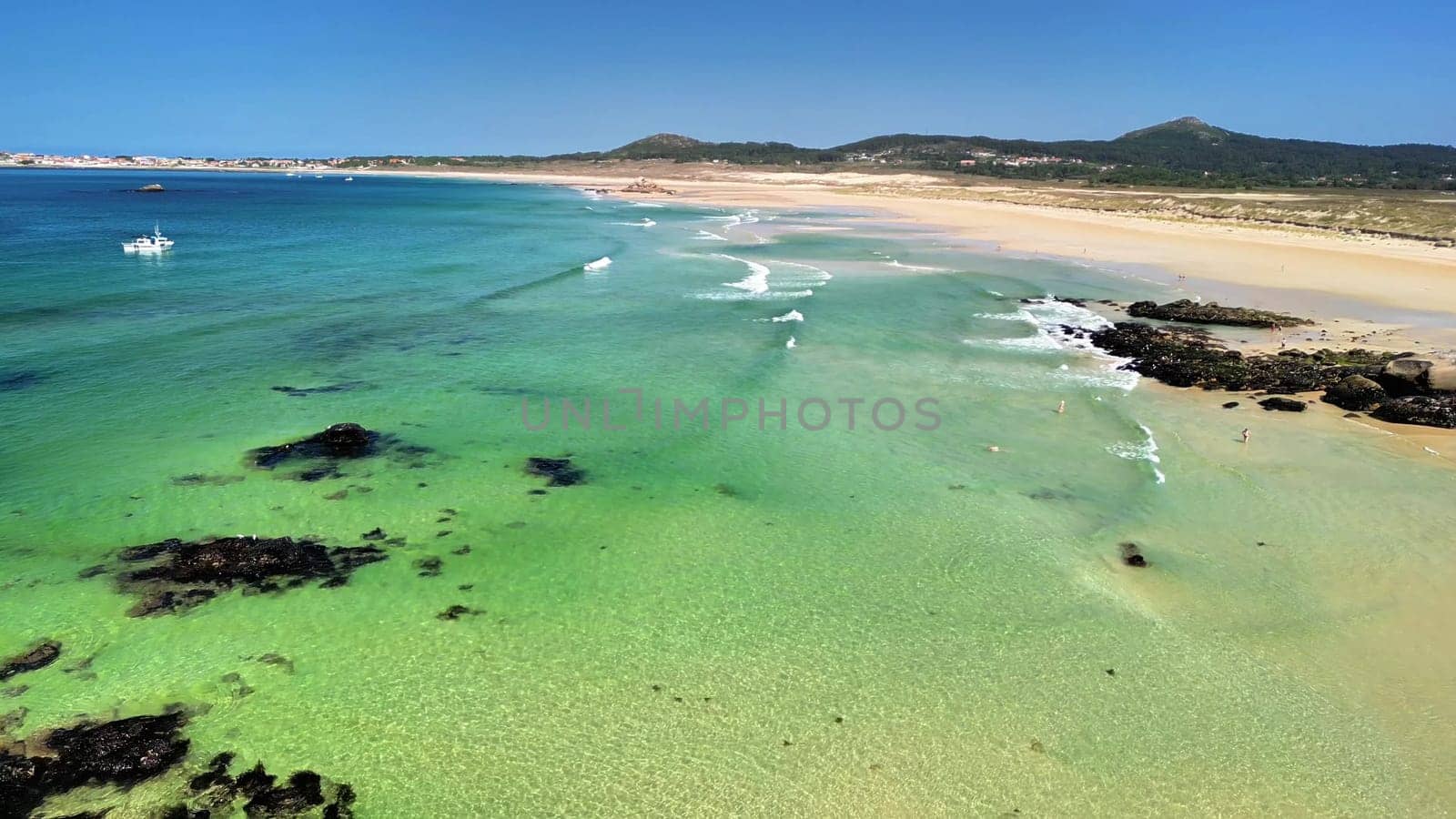 An aerial photograph captures a picturesque beach scene with vibrant turquoise waters and inviting soft sandy shores