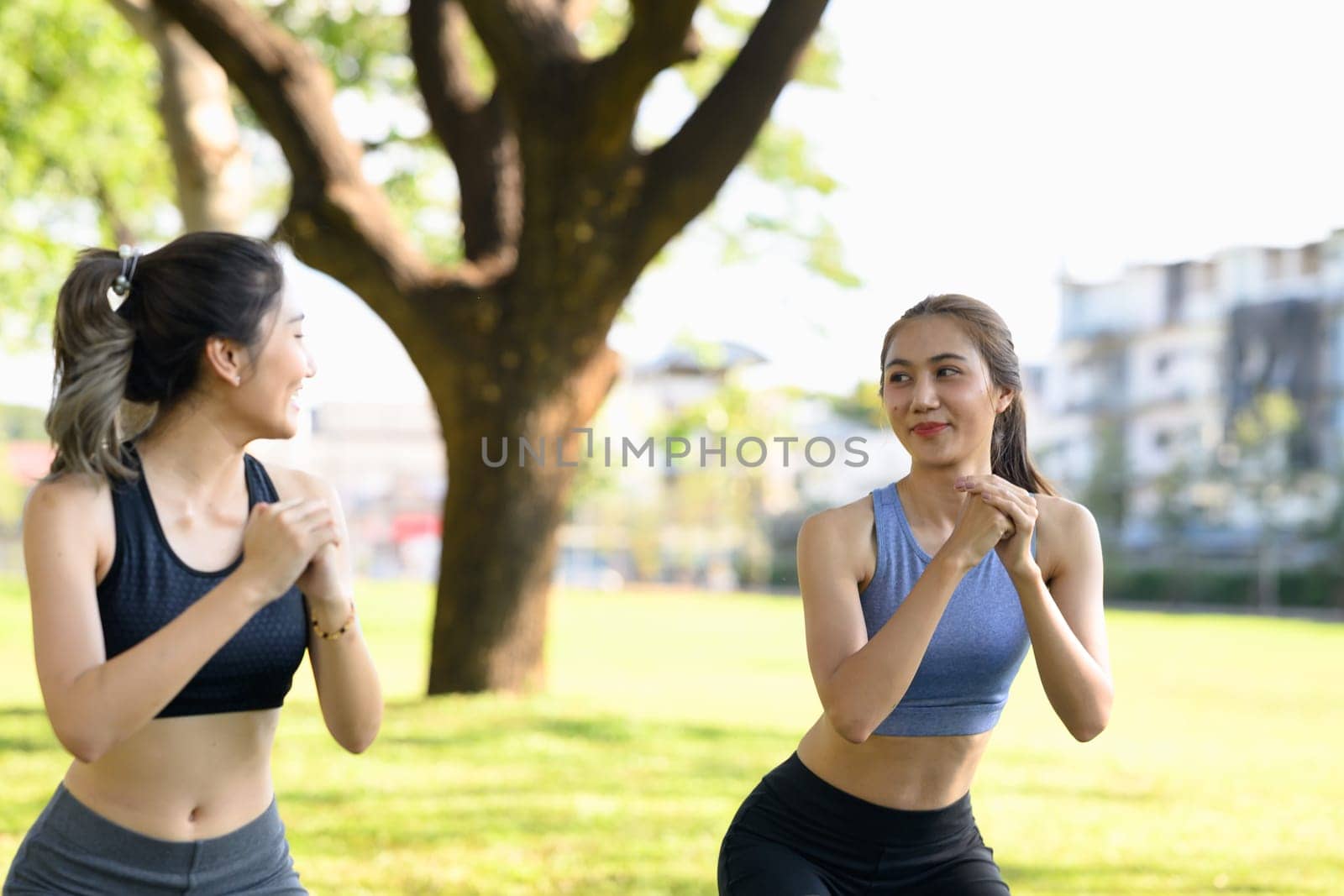 Fit Asian women in sportswear working out together in nature.