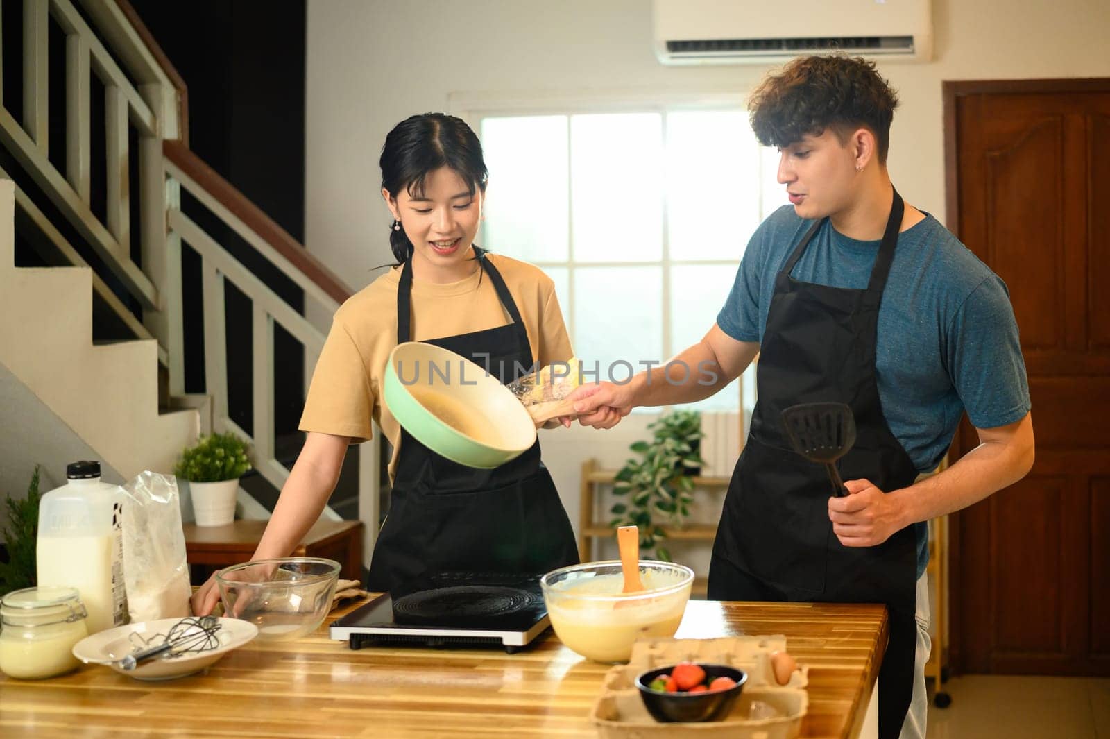 Happy couple preparing to cook pancakes together in a cozy kitchen.