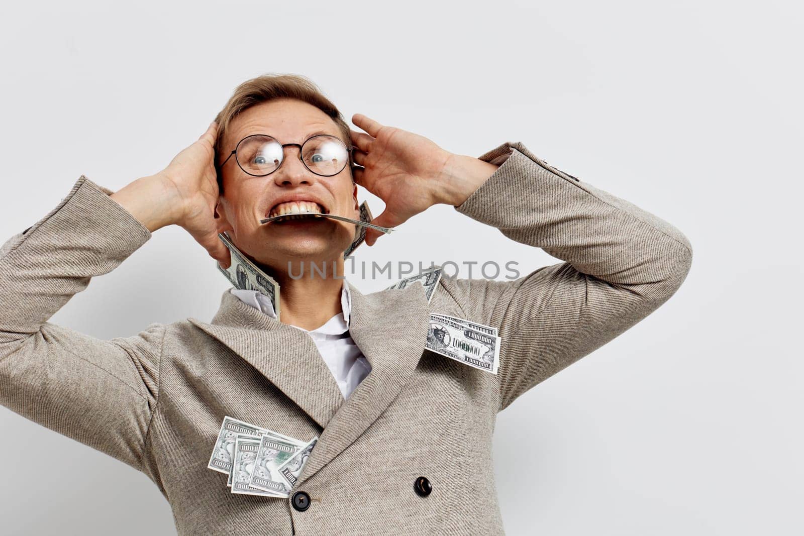 excited man with glasses wearing beige jacket holding cash currency notes and celebrating success with joyful emotion on white studio background digital nomad lifestyle concept